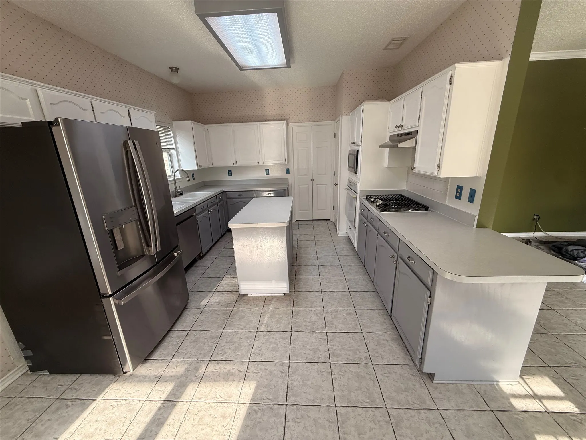 Kitchen featuring white upper cabinetry, gray lower cabinetry, a center island, and tile flooring