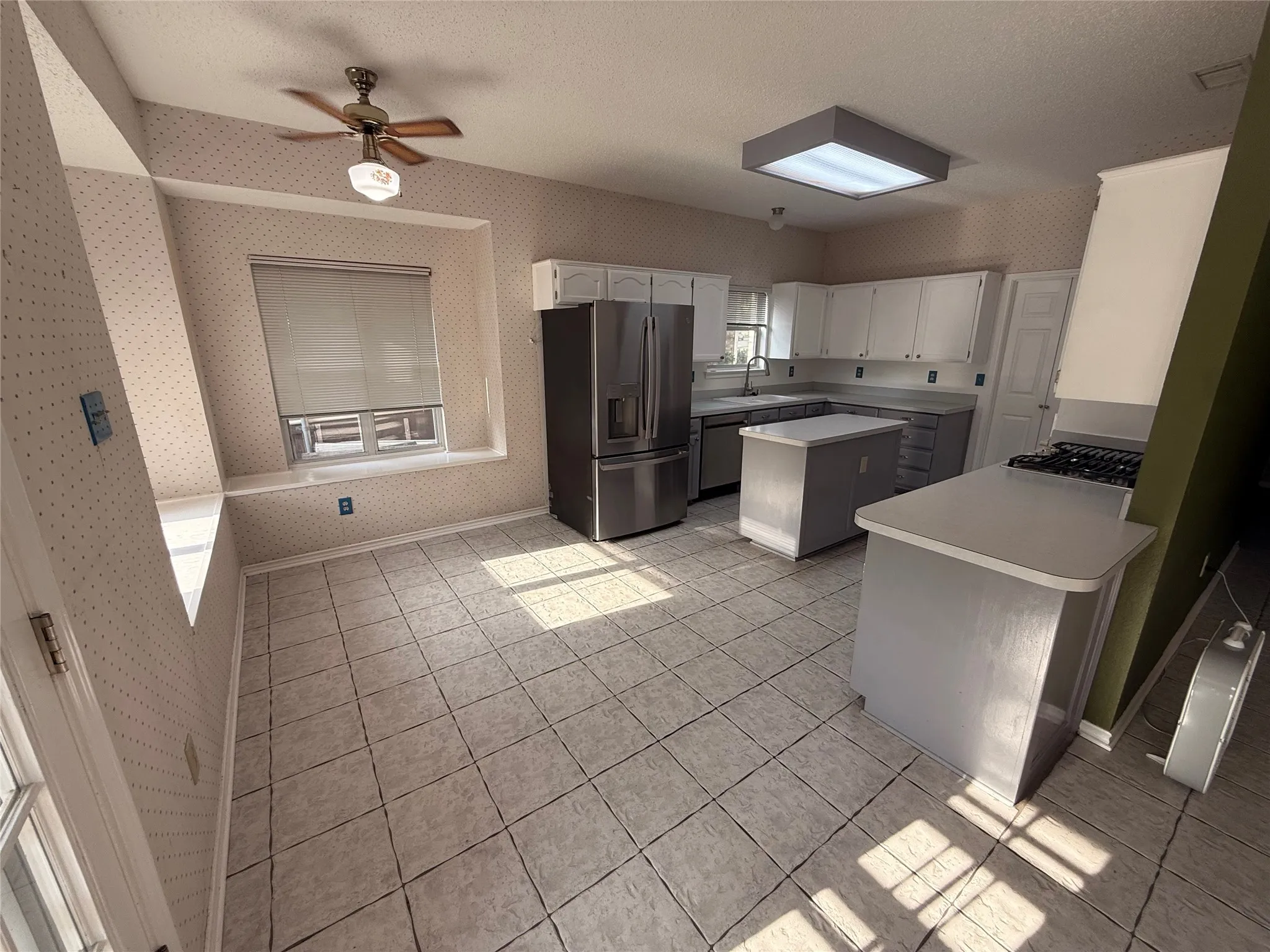 Spacious kitchen featuring stainless steel appliances, white cabinetry, tile flooring, and ample counter space