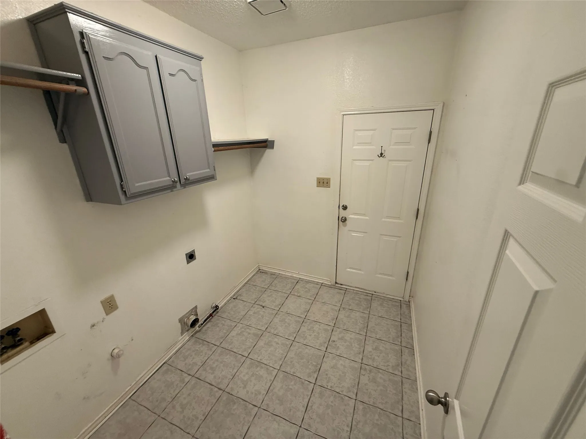 Tile flooring, wall-mounted cabinetry, and a utility door