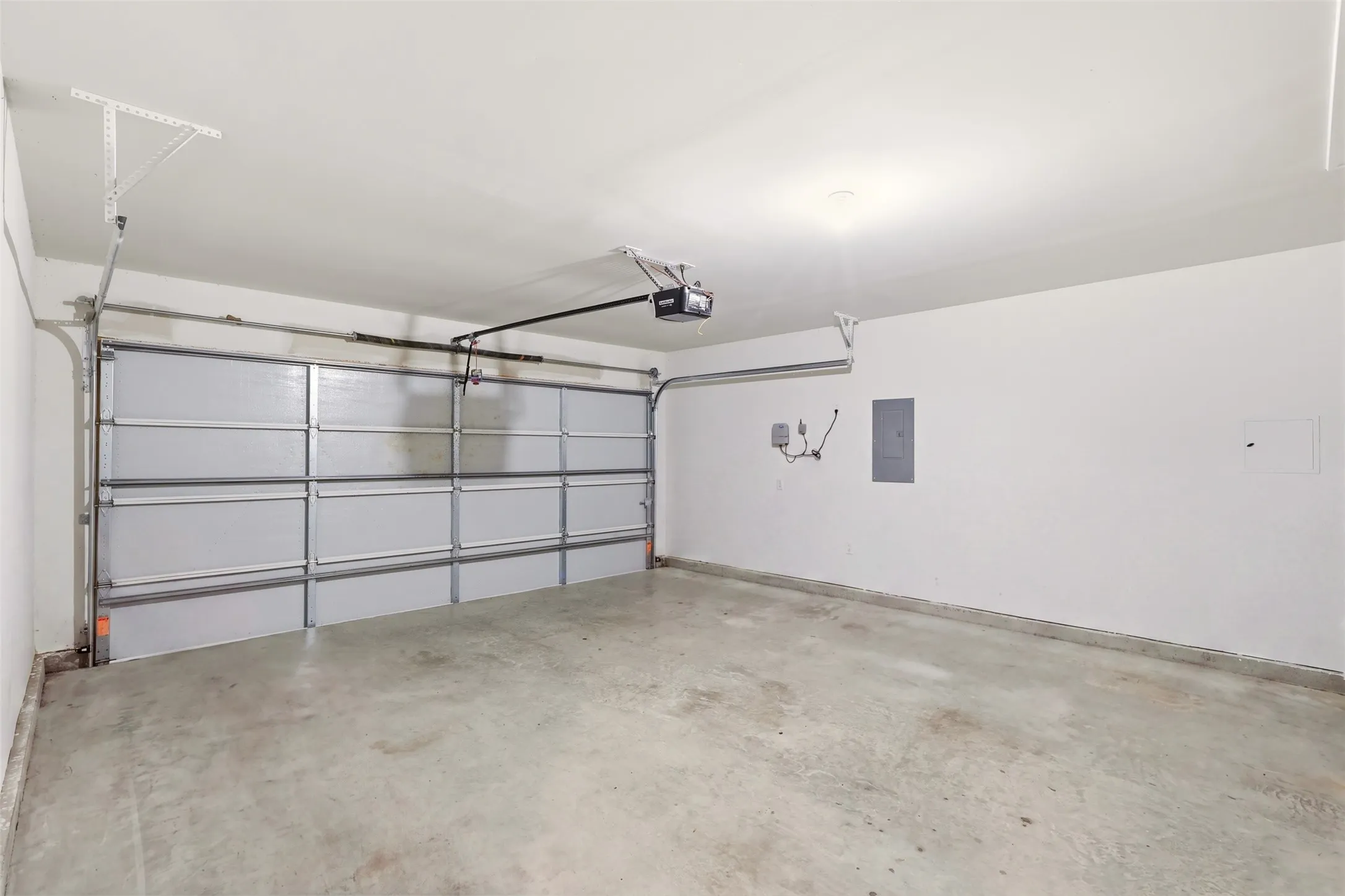 Attached garage with concrete flooring, automatic garage door opener, and white painted walls