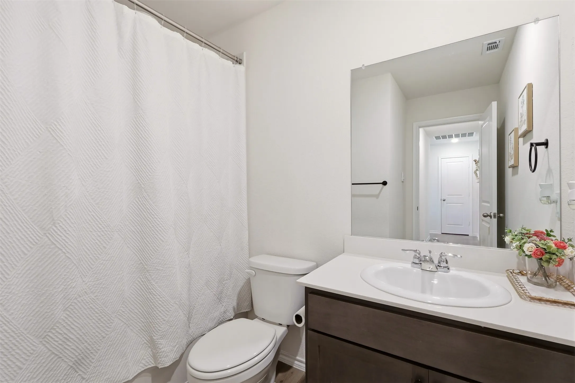White vanity with dark wood-finish cabinetry, a white countertop, and an oval undermount sink