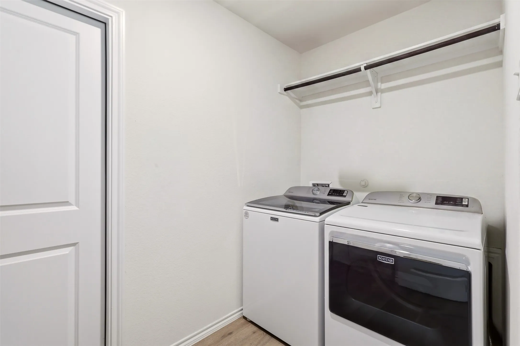Laundry area with wood-finish flooring and a built-in hanging rod