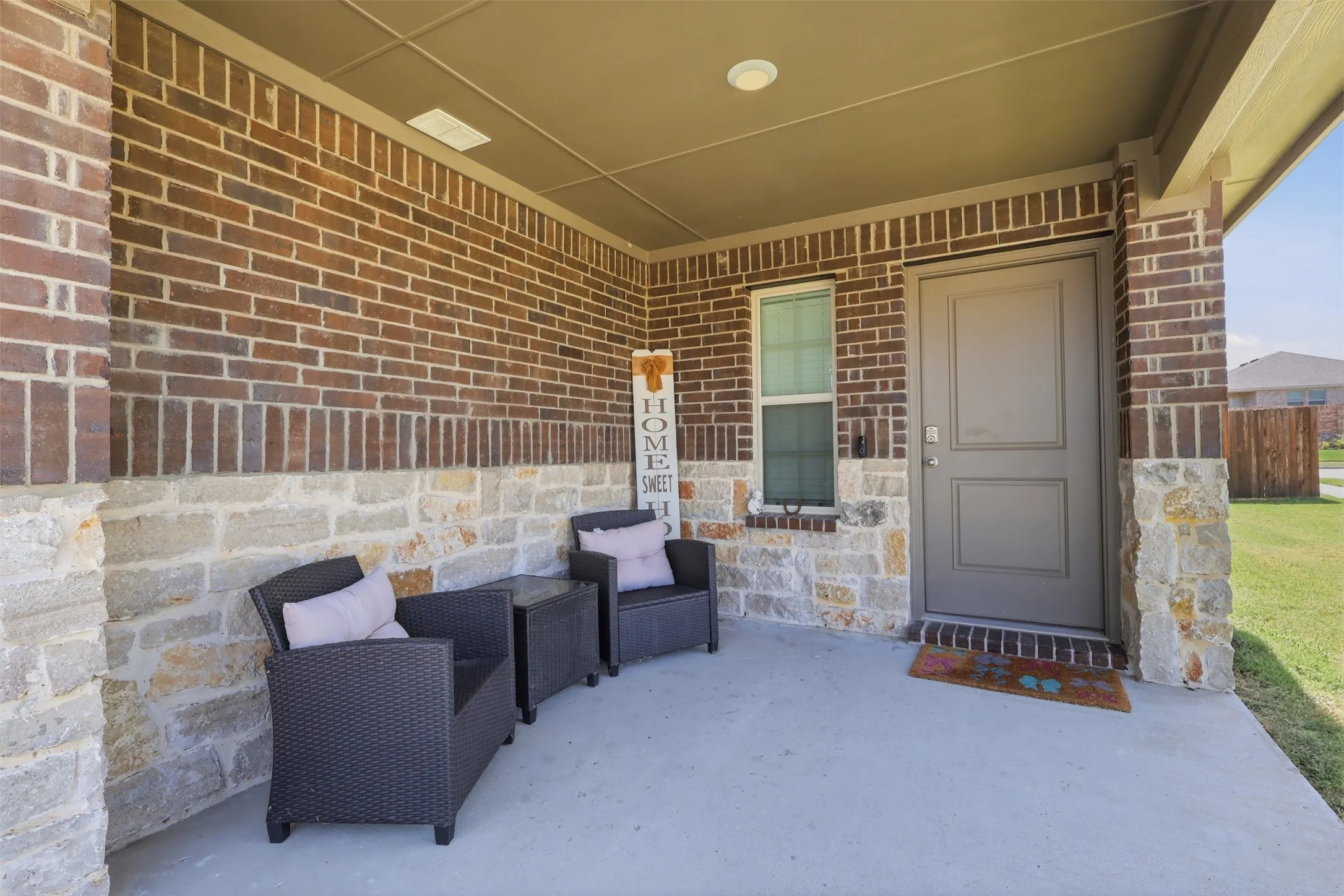 Brick exterior front porch with stone accents, covered entry, and a paneled front door