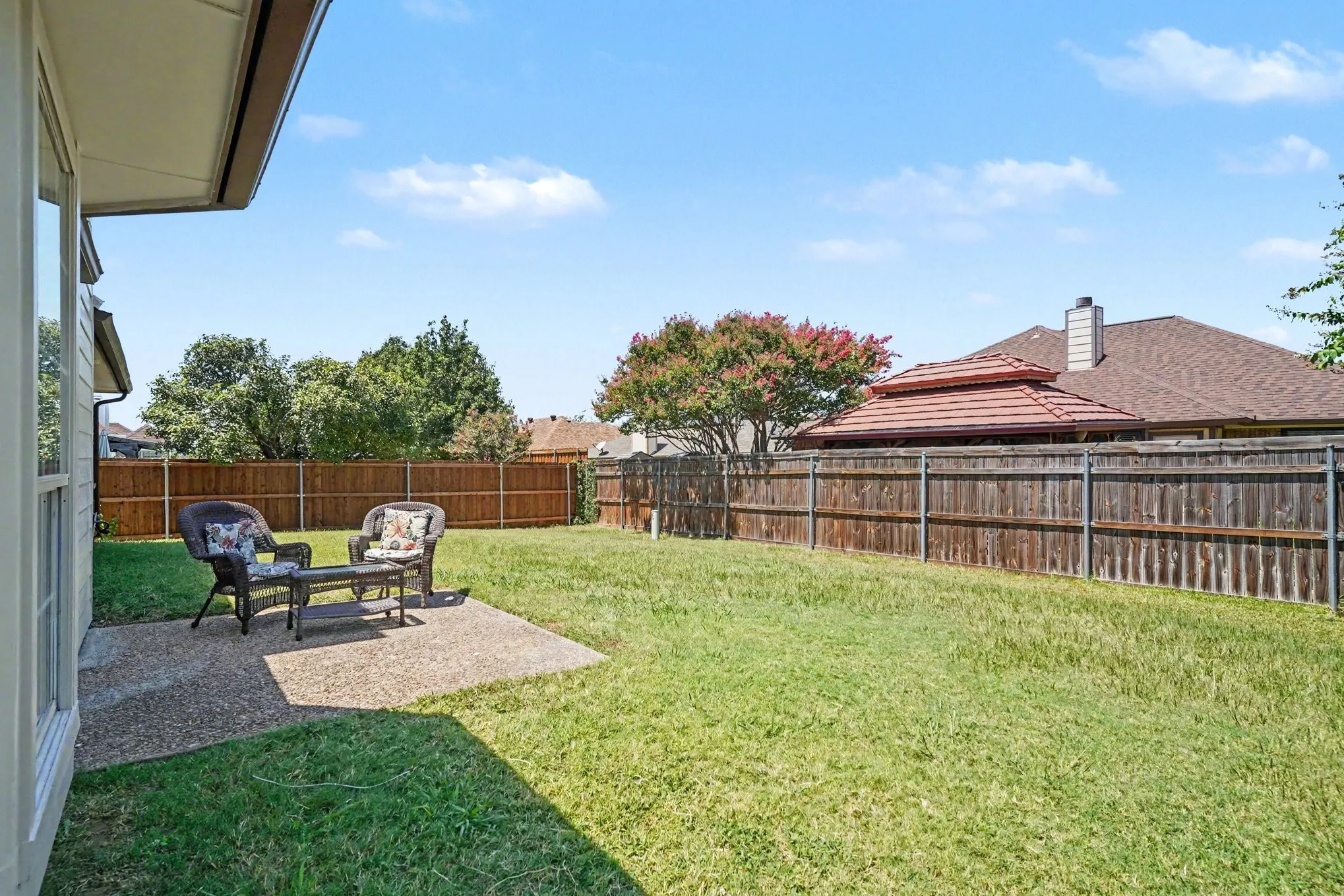 Expansive backyard featuring a concrete patio, wood fencing, and established trees