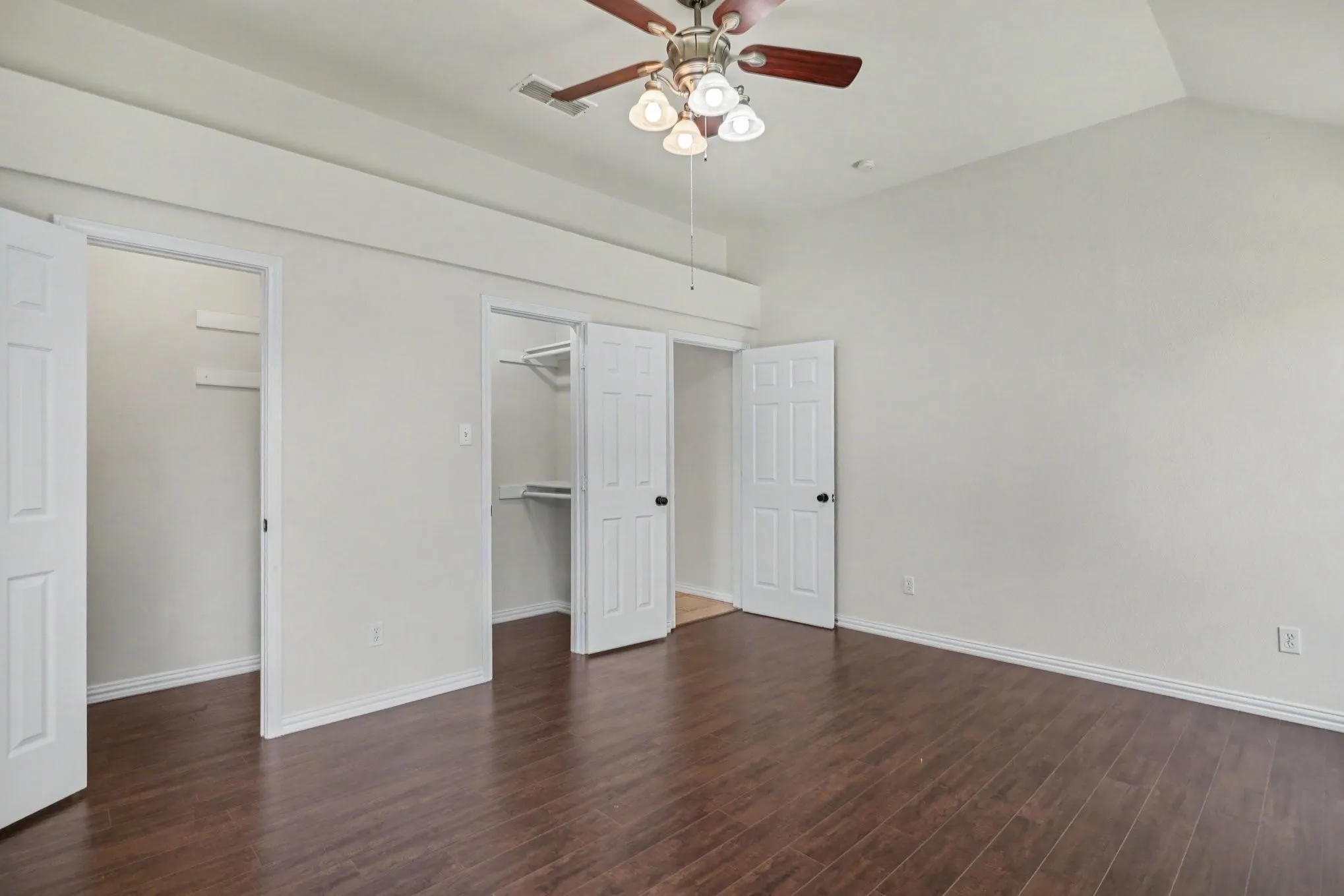 Vaulted ceiling with a ceiling fan, dark wood-finish flooring, and white interior doors
