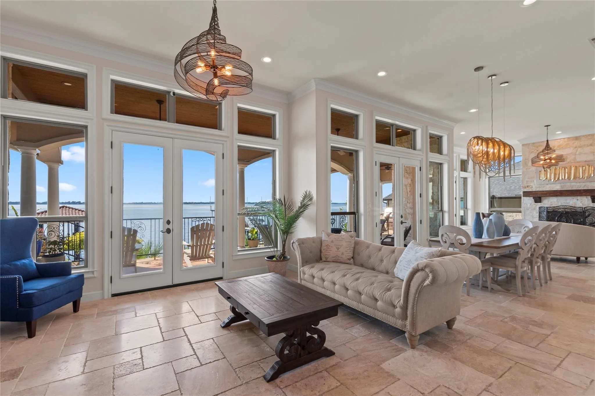 Expansive windows frame open-water views across two living areas with a spacious dining area and butlers pantry