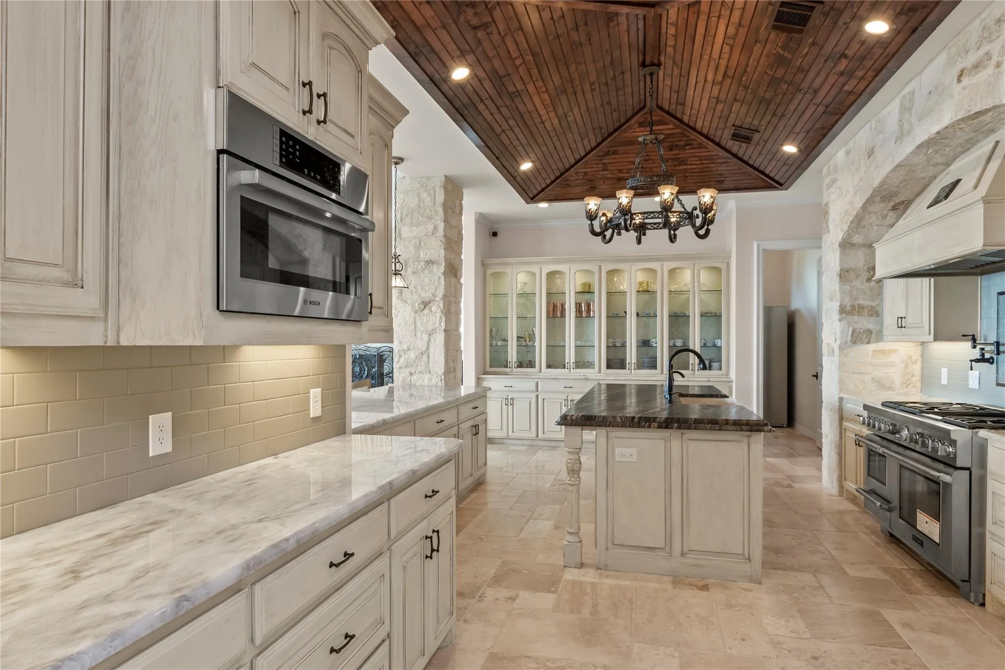 Thermador 6-burner gas range with pot filler framed in stone accents.