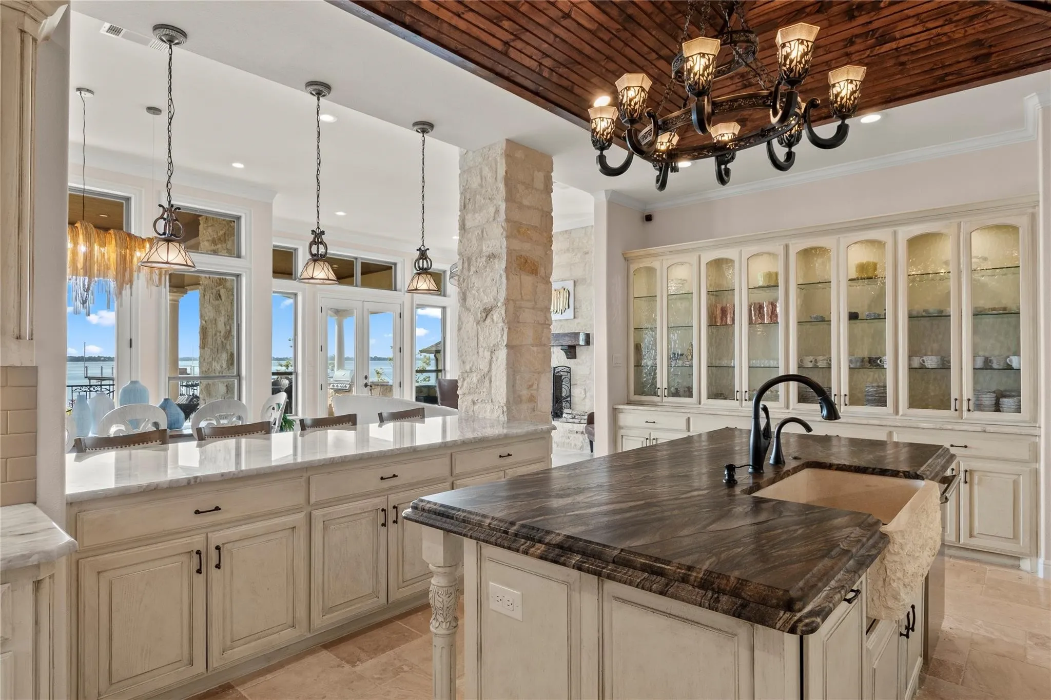 Cook with a view—panoramic water scenes framed by stone accents and a warm wood ceiling. Custom cabinetry with aesthetic appealing glass fronts for decorative display and amazing amount of storage.