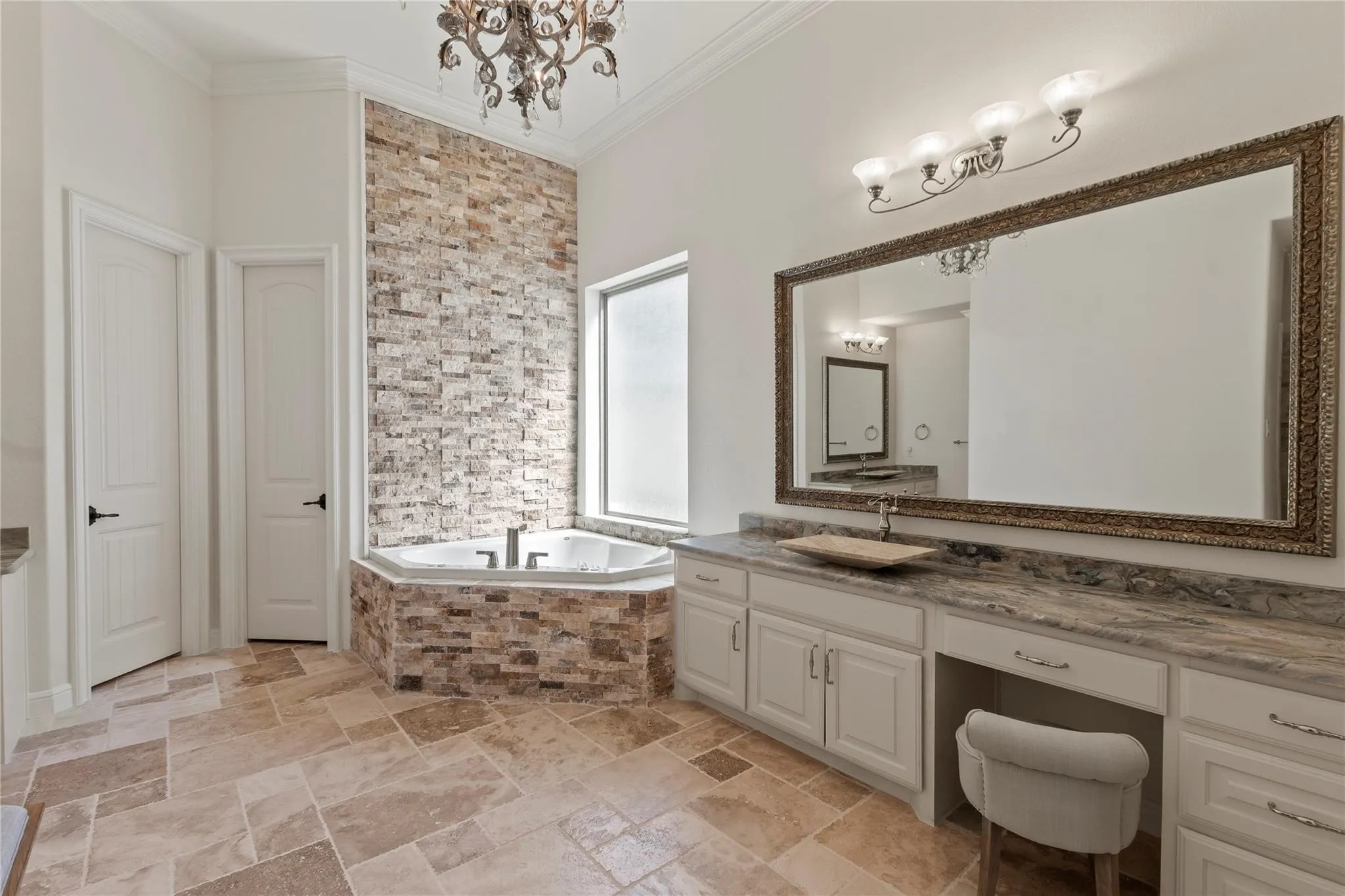 Spa-like ensuite with dual vanities, stacked-stone soaking tub, spacious tiled shower and two walk-in closets.
