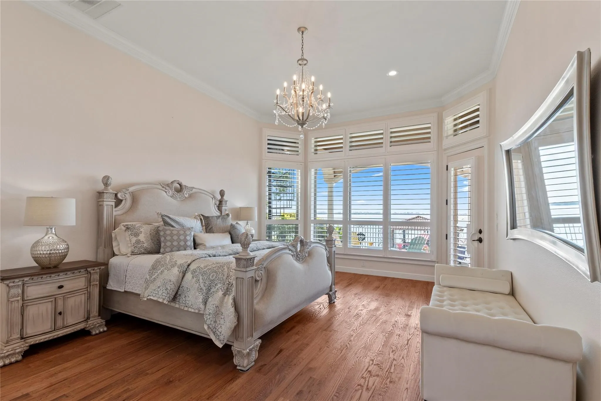 Waterside Primary suite featuring wood floors, wall of windows with plantation shutters.