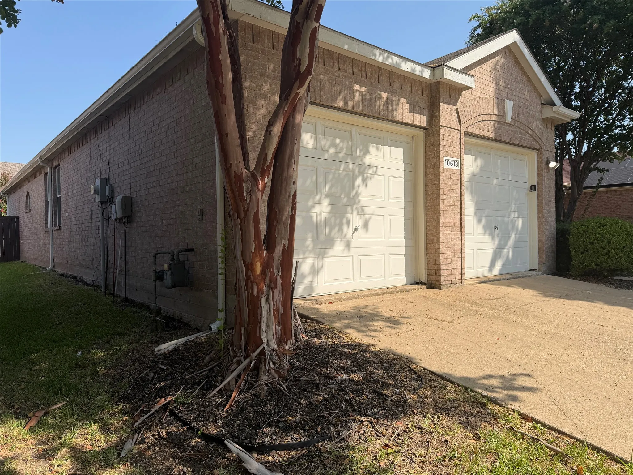 Brick exterior with two white garage doors and an arched entryway