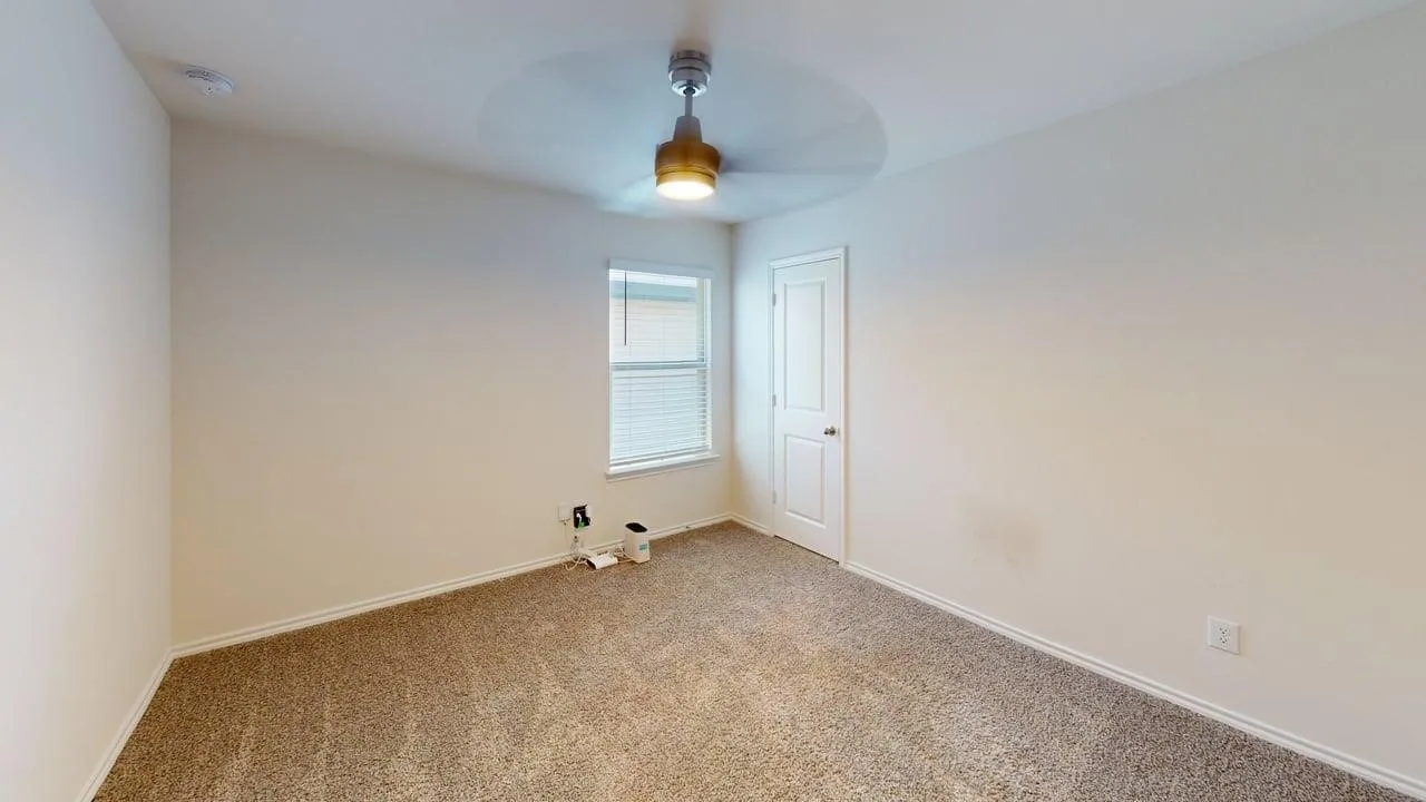 Wall-to-wall carpeting, neutral wall finishes, window with blinds, and a ceiling fan with integrated lighting
