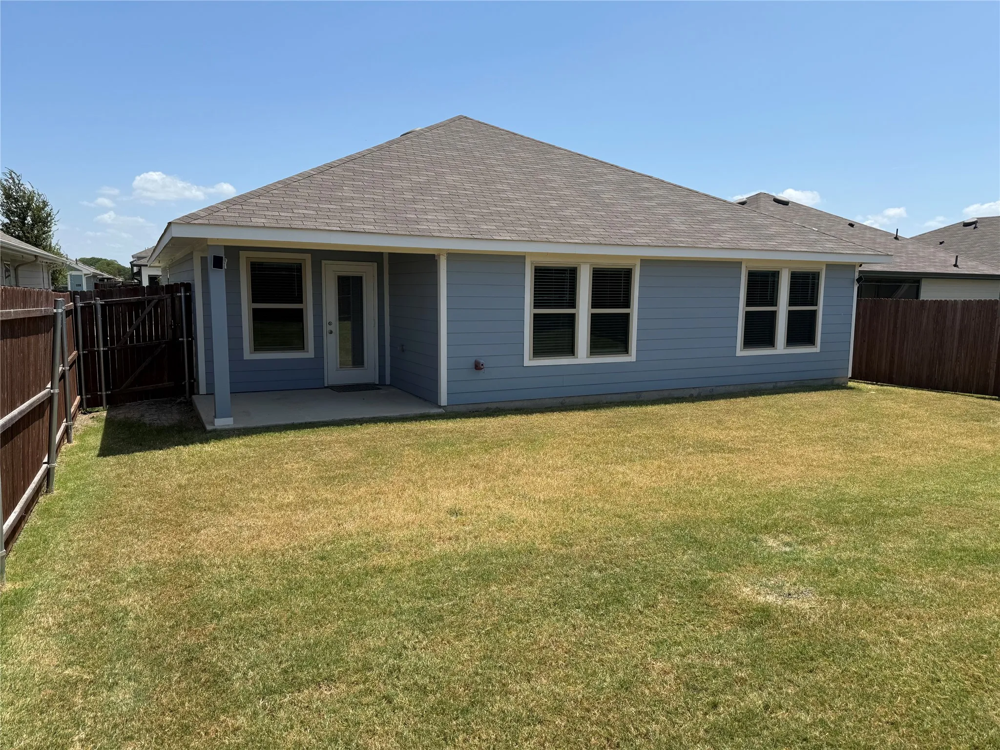 Rear exterior with blue siding, a covered patio, and a privacy fence