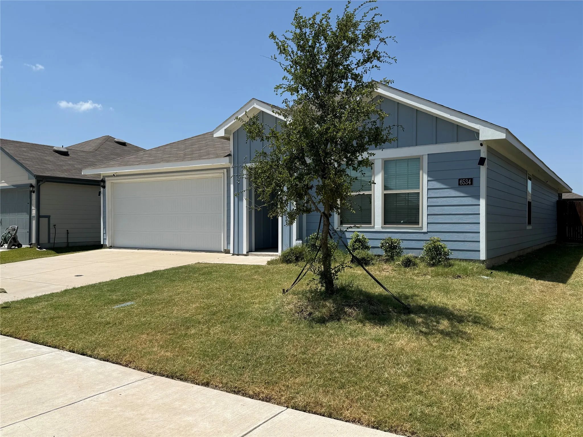Light blue siding exterior with white trim, a single-car garage, and a concrete driveway