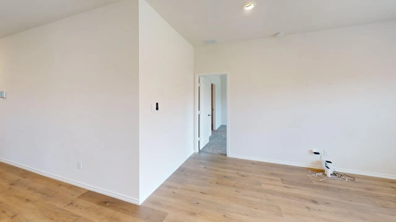 Wood-finish flooring, recessed ceiling lighting, and crisp white walls provide a neutral palette