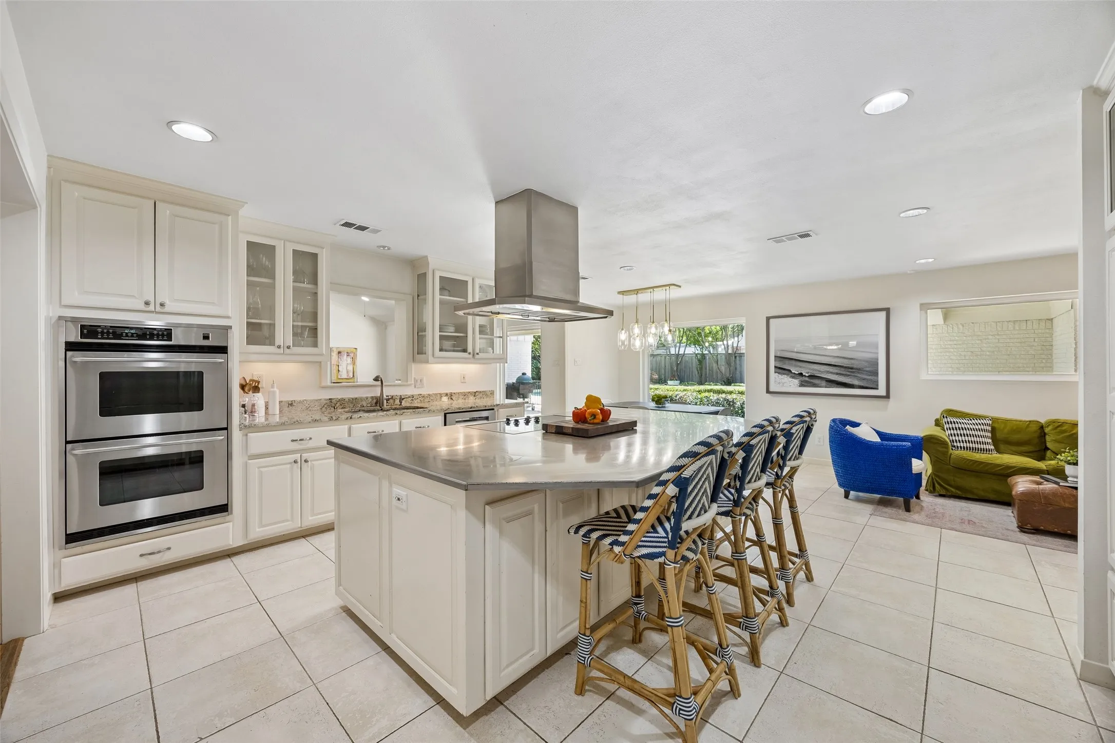 Spacious kitchen centers around an oversized island with seating, double ovens, abundant cabinetry, and an open connection to the casual living and dining areas.