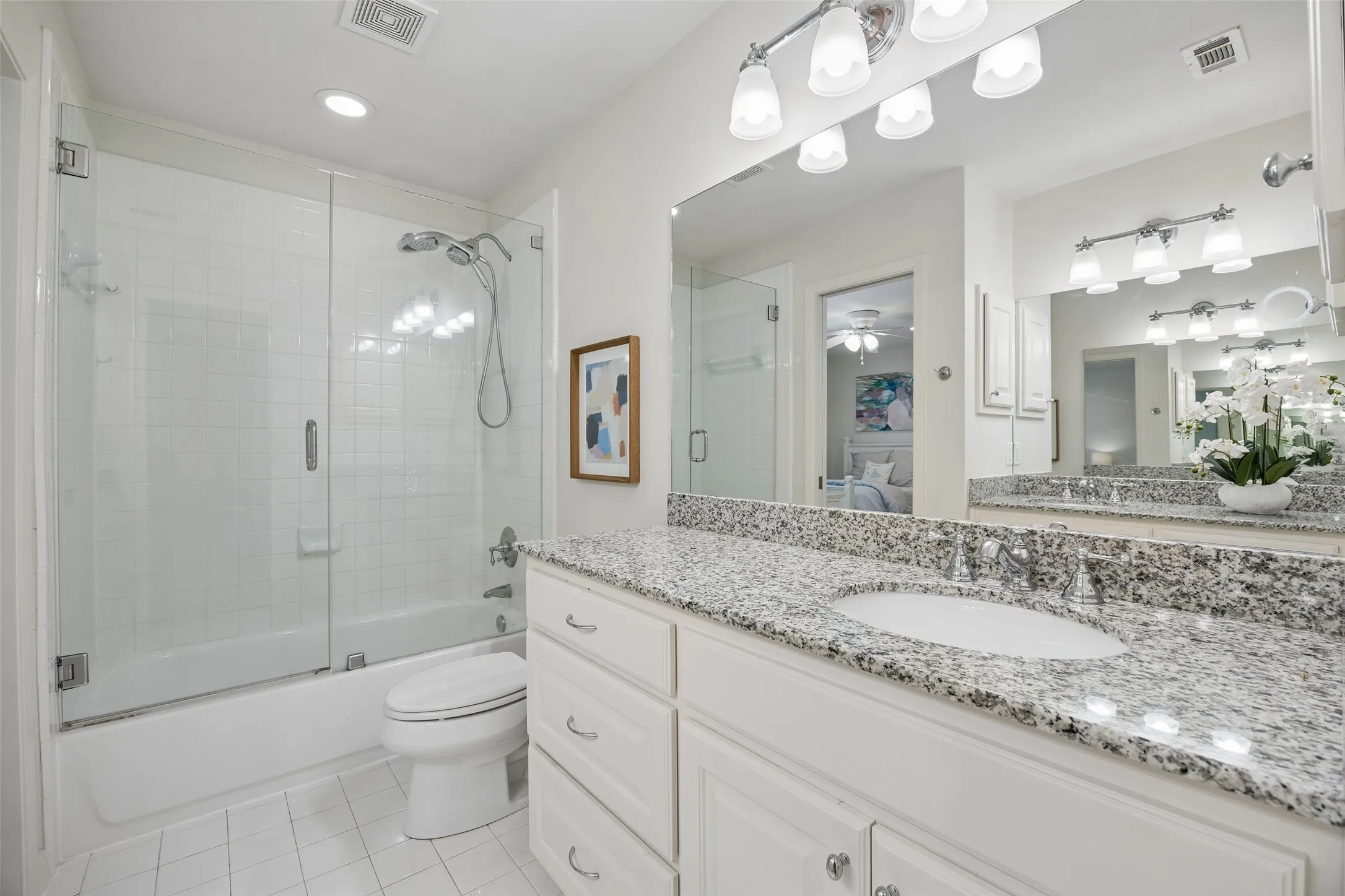 A second view of the upstairs Jack-and-Jill bath highlights the tub-shower combination, granite-topped vanity, and generous storage.