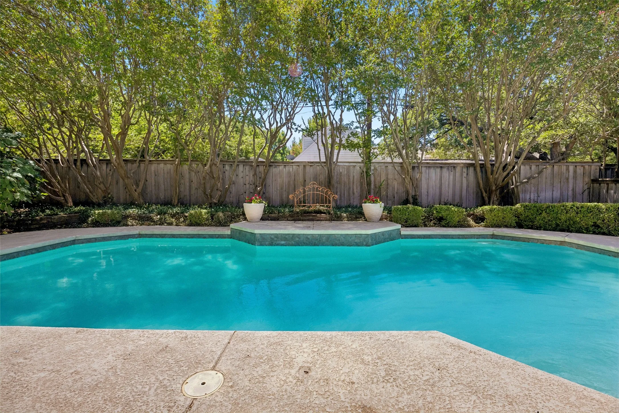 The expansive backyard pool is framed by mature trees and lush landscaping, creating a serene setting for outdoor living and entertaining. Additonal green space not photographed.
