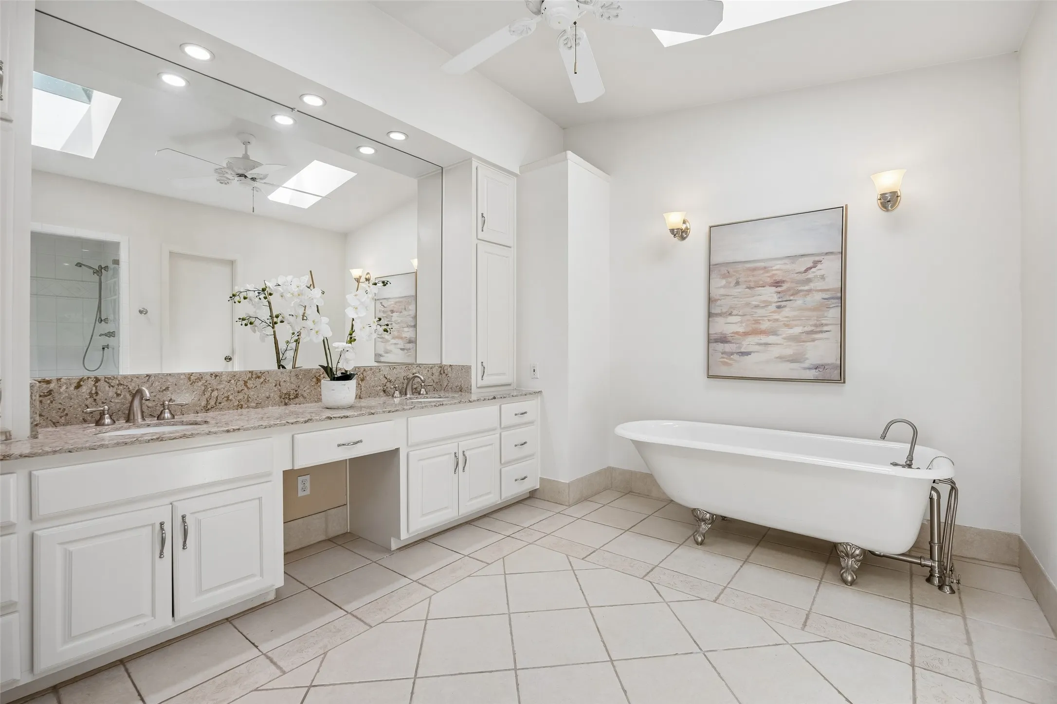 The spacious primary bathroom with a freestanding soaking tub, dual vanities, frameless shower, abundant storage, and skylights that fill the space with natural light.