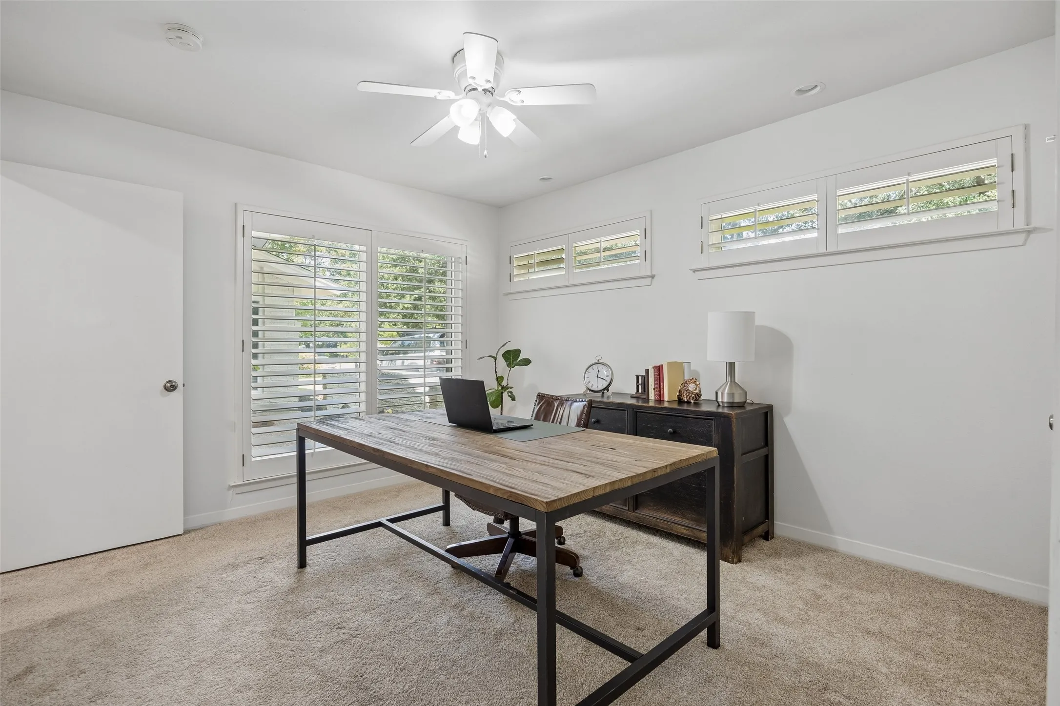 A downstairs bedroom currently used as an office offers abundant natural light and flexible functionality.