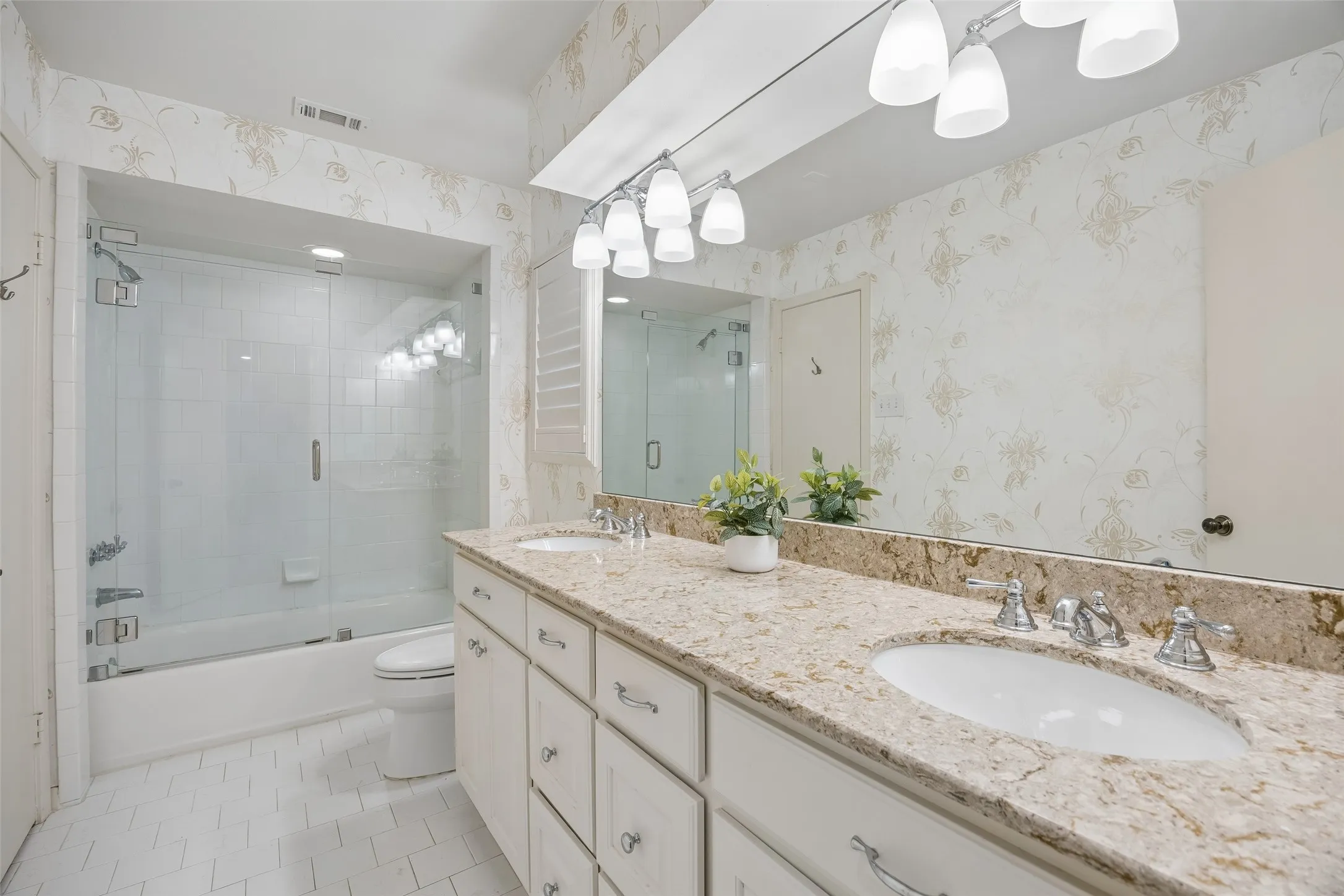 The downstairs Jack-and-Jill bath features dual sinks, a generous vanity and a tub-shower combination with frameless glass.