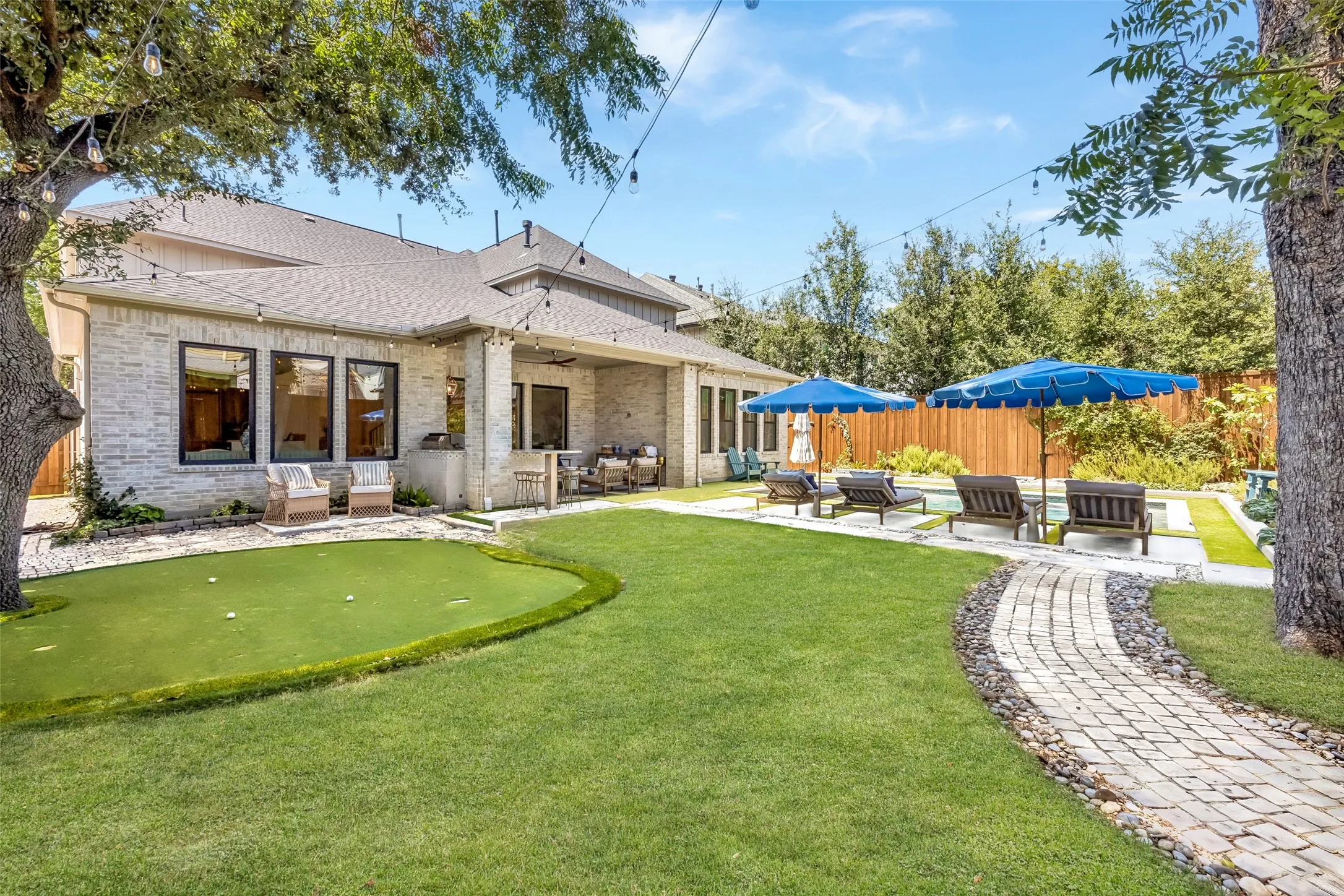 A beautifully landscaped backyard is designed for both recreation and entertaining, with a sparkling pool, putting green, covered outdoor living area, mature trees and generous lawn space.
