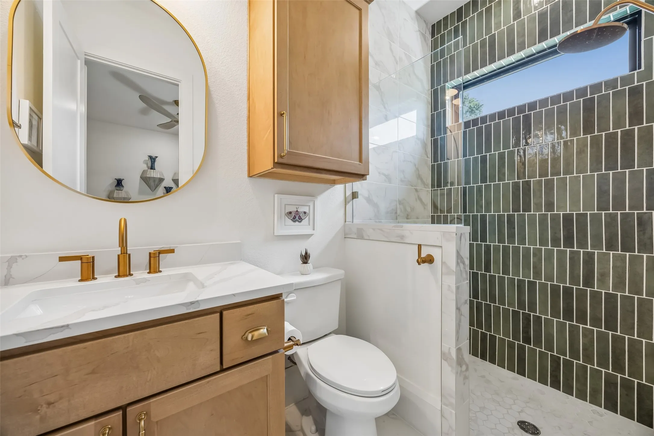 A stylish en suite bath features warm wood cabinetry, brass fixtures and a glass-enclosed shower accented with striking designer tile.