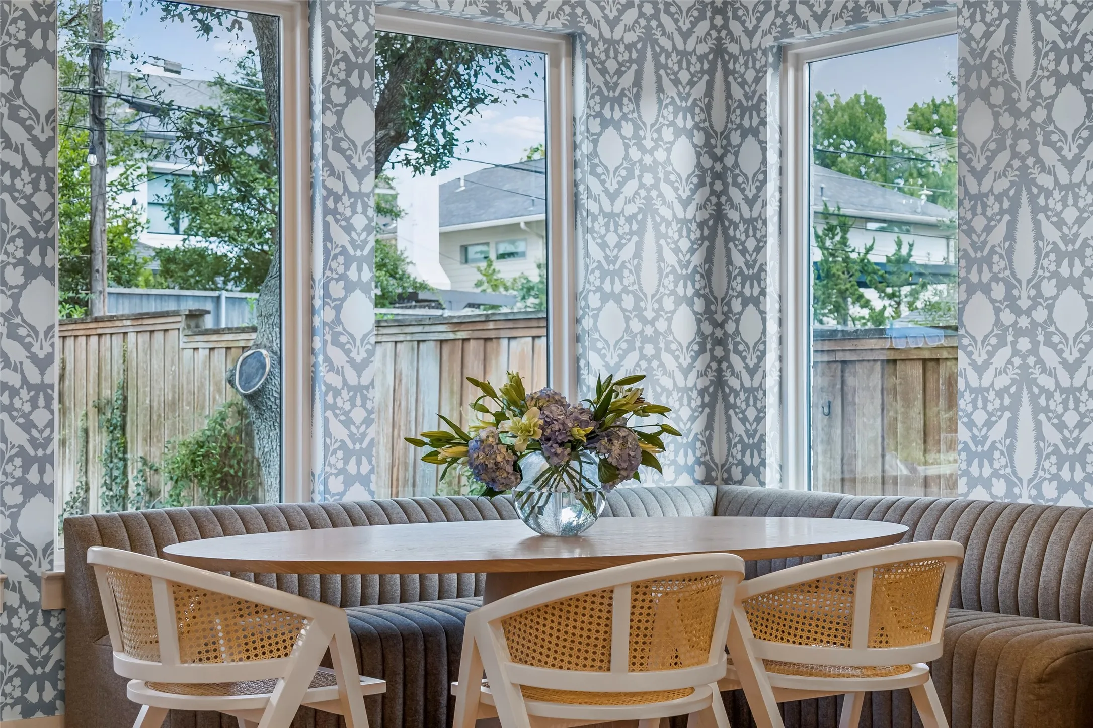 A charming breakfast nook makes a memorable design statement with designer wallcovering and walls of windows that fill the space with natural light.