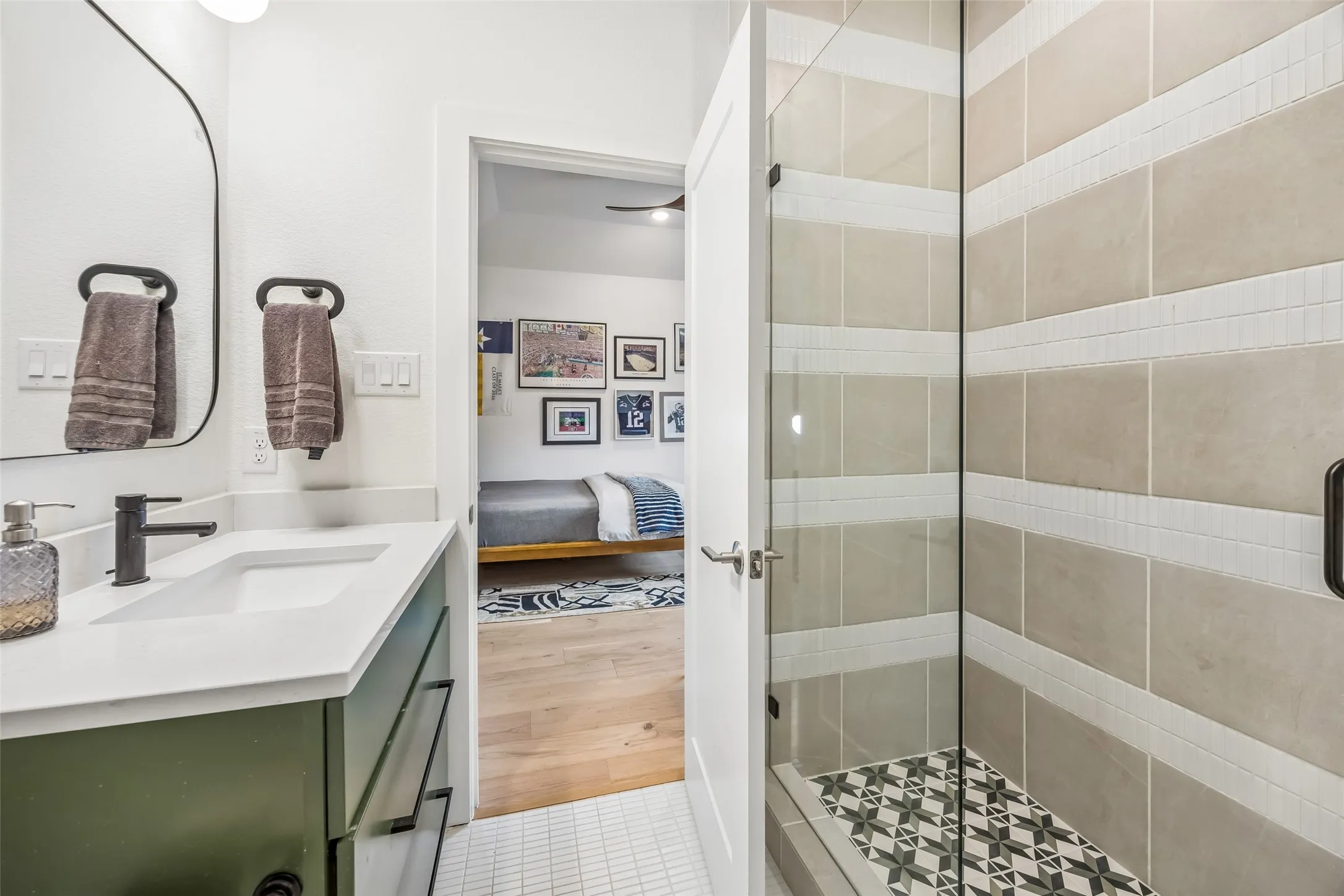 An en suite bath features a modern vanity, glass-enclosed shower and distinctive designer tilework for a polished, custom feel.