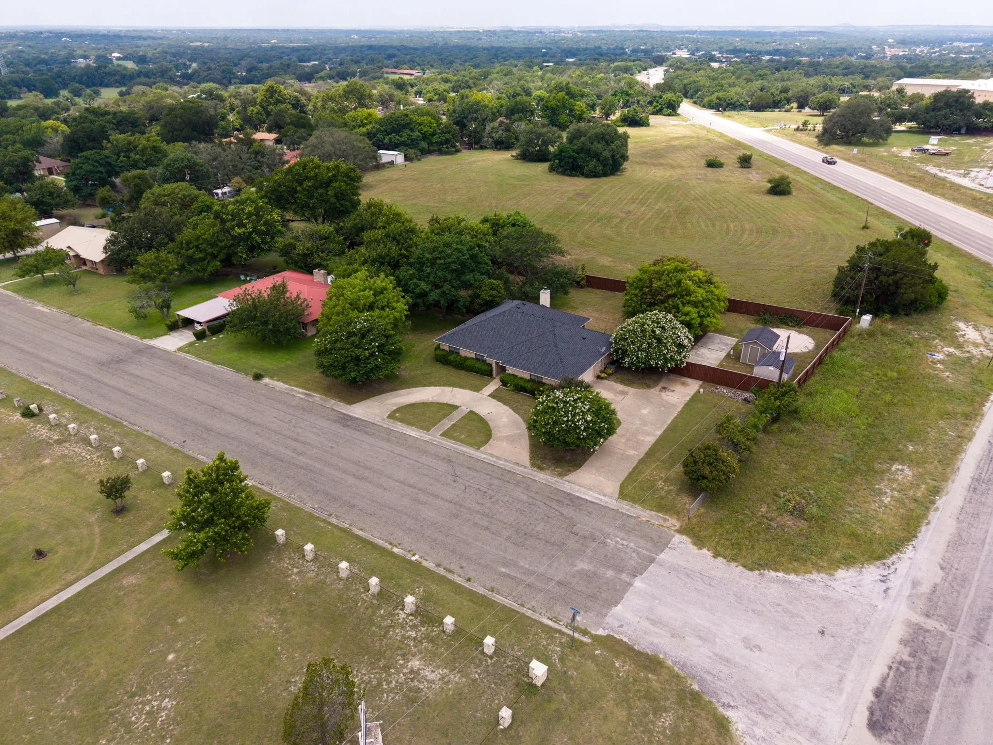 Single-story residence with a dark shingle roof, paved driveway, and established perimeter fencing