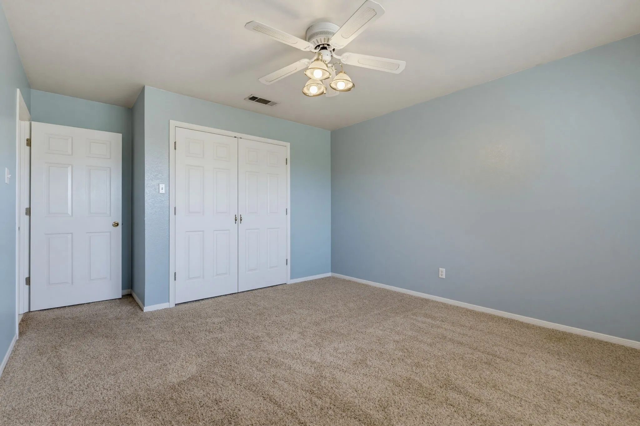 Wall-to-wall carpet flooring, light blue wall finishes, white trim, and a ceiling fan with integrated lighting