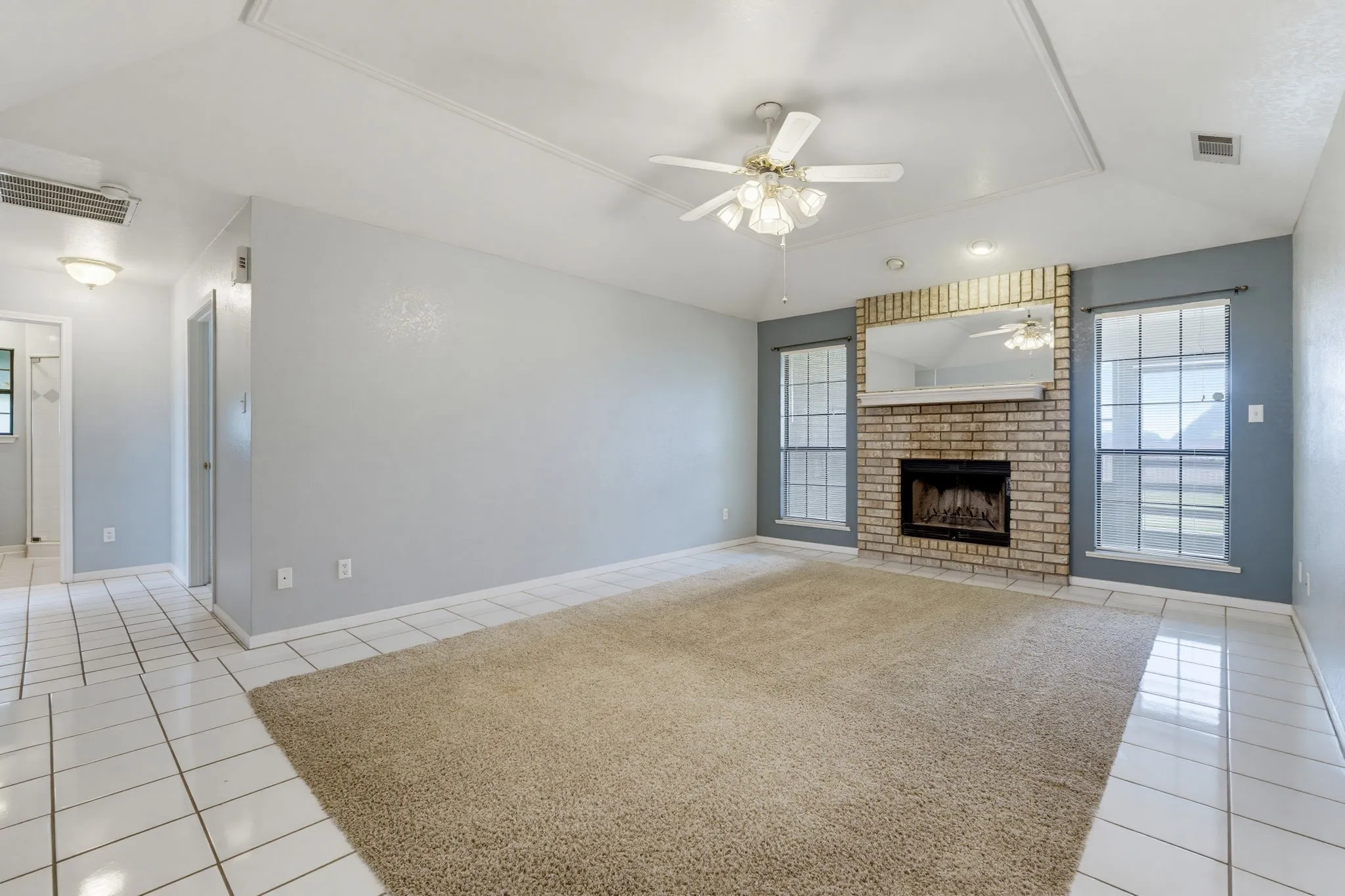 Brick fireplace with a hearth, coffered ceiling, and ceiling fan