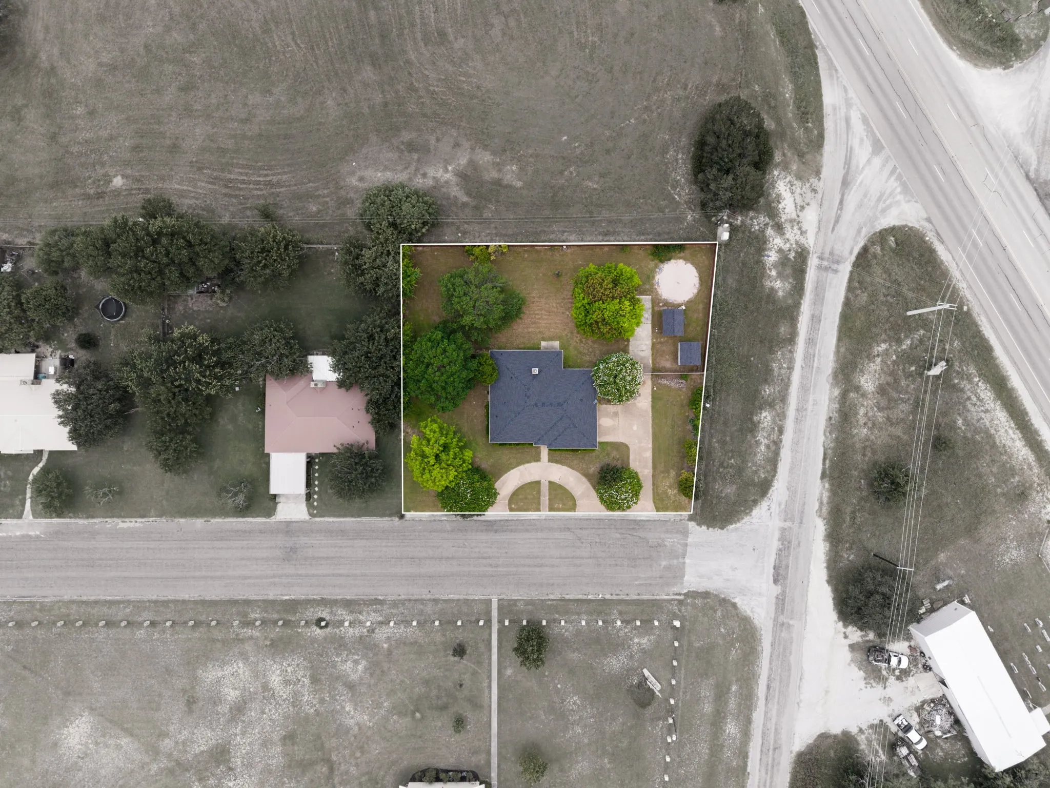 Paved circular driveway, mature trees, and a dark shingle roof