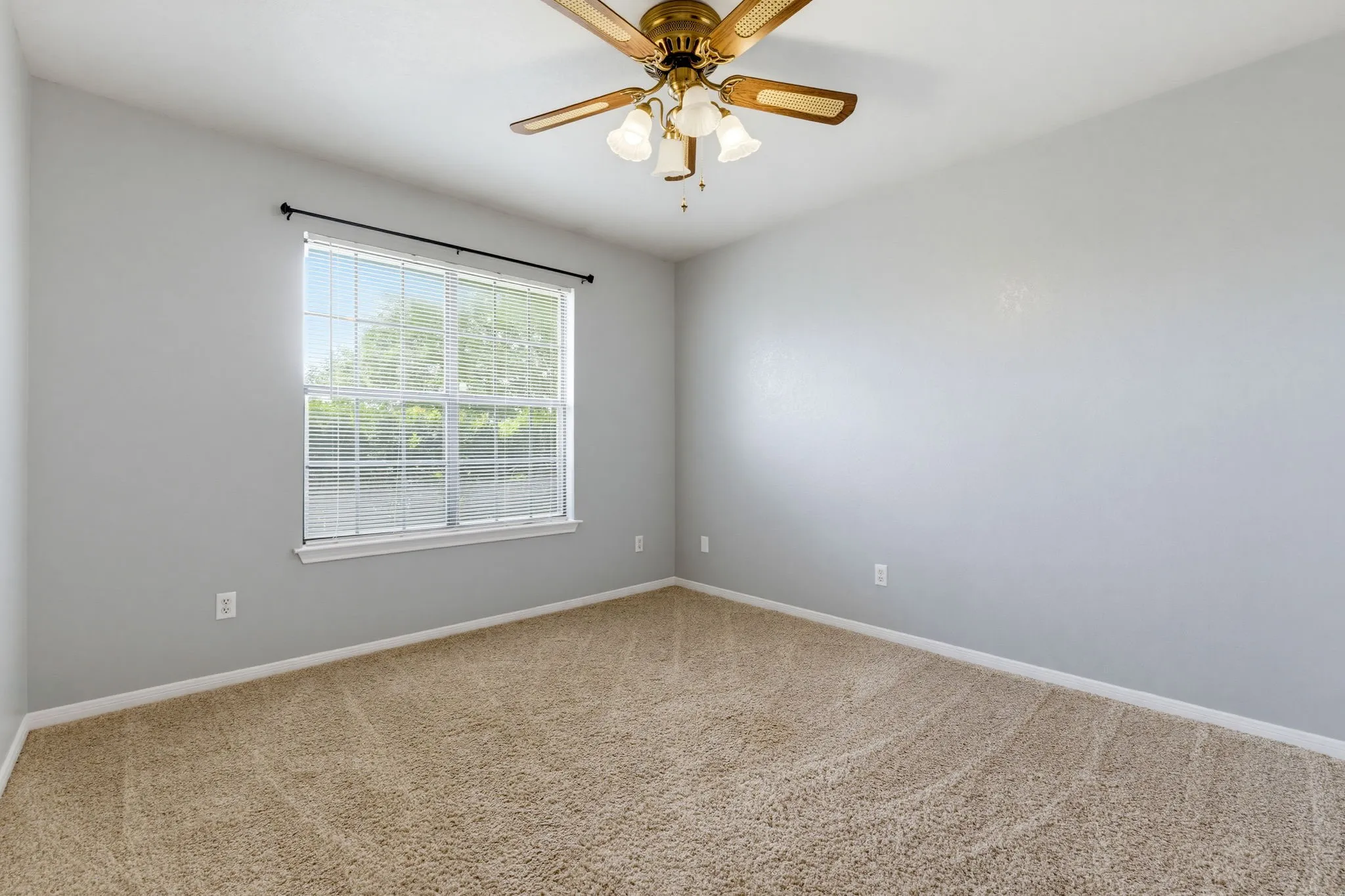 Neutral wall paint, carpeted flooring, large window with blinds, and a ceiling fan with integrated lighting