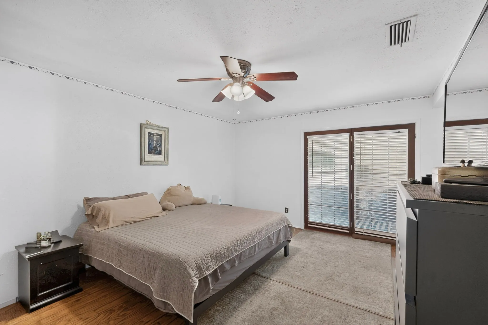 Wood-finish flooring, sliding glass door, ceiling fan with light fixture, and textured ceiling