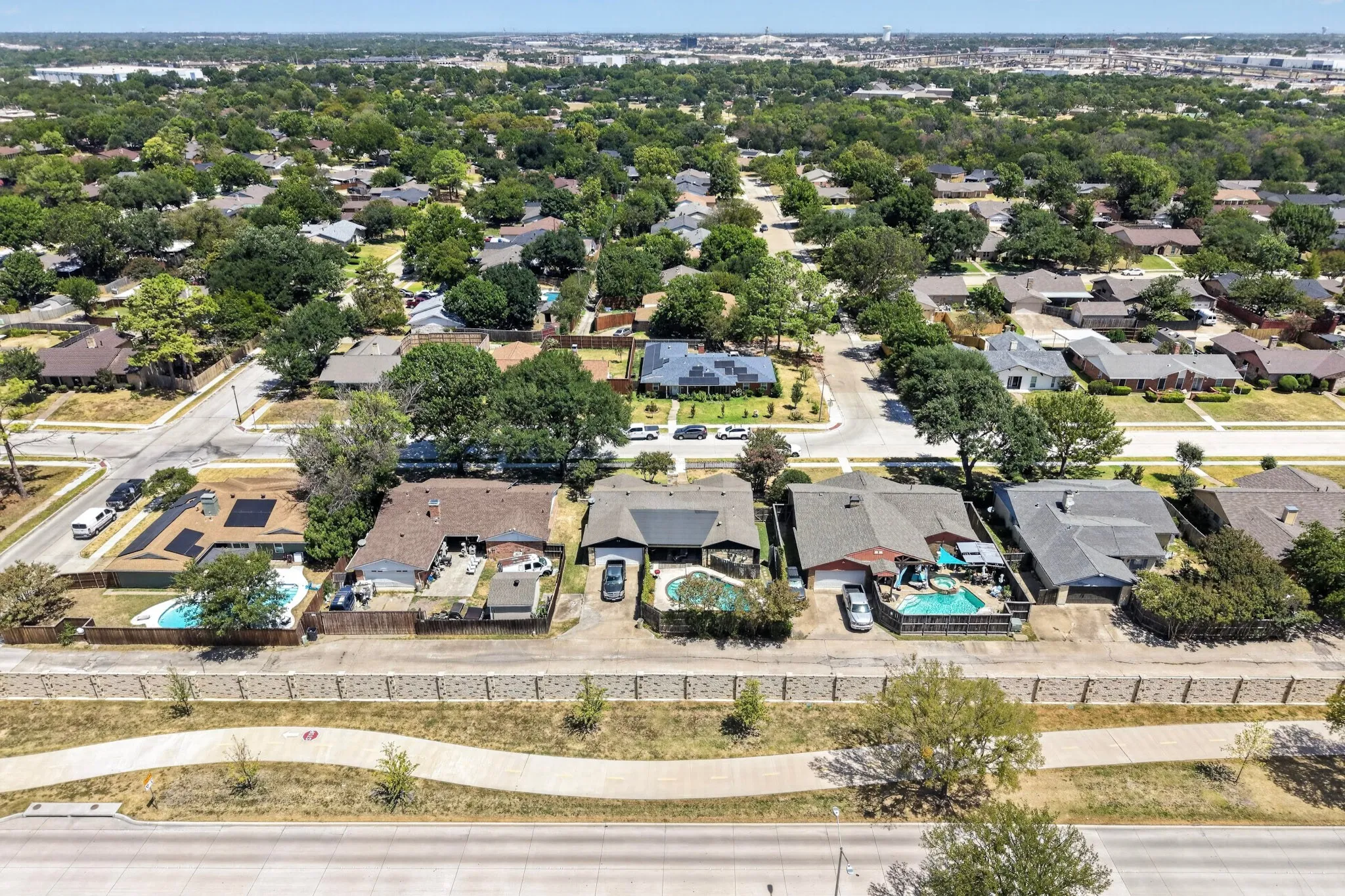 Residential neighborhood with mature trees and visible swimming pools