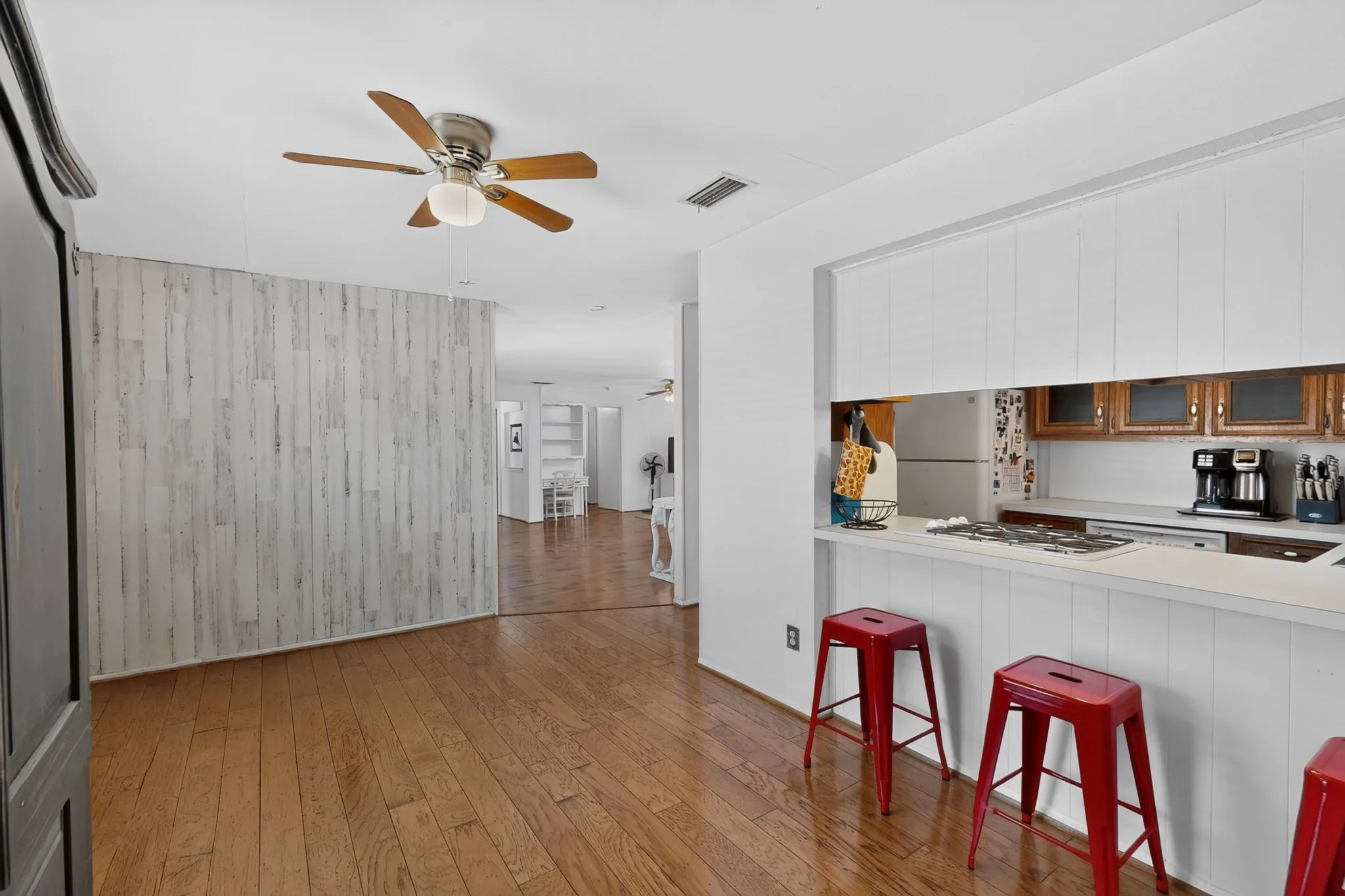 Wood-finish flooring throughout, bright white ceiling, and a ceiling fan with integrated lighting