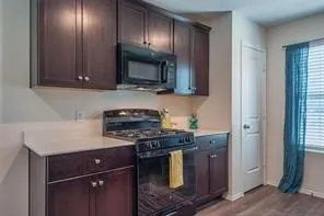 Dark wood-finish cabinetry, light-toned countertops, and a black range with an integrated microwave
