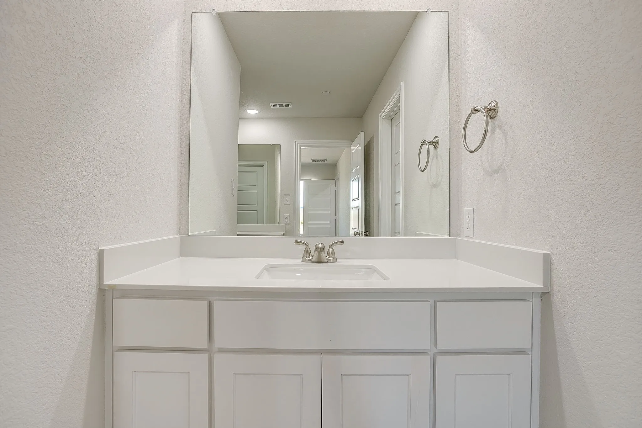 Bathroom featuring a textured wall and vanity