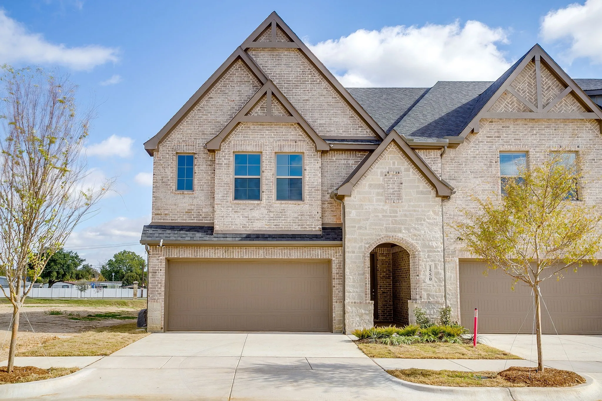 View of front of property featuring brick siding, roof with shingles, an attached garage, and driveway