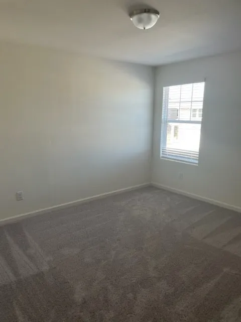 Neutral-toned carpeting, white walls, and a window with blinds