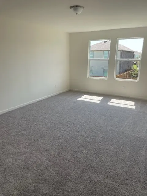 Spacious room featuring gray carpet, white walls, and two windows