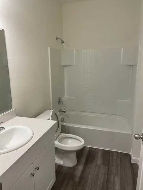 White vanity with integrated sink, light-toned countertop, and wood-finish flooring