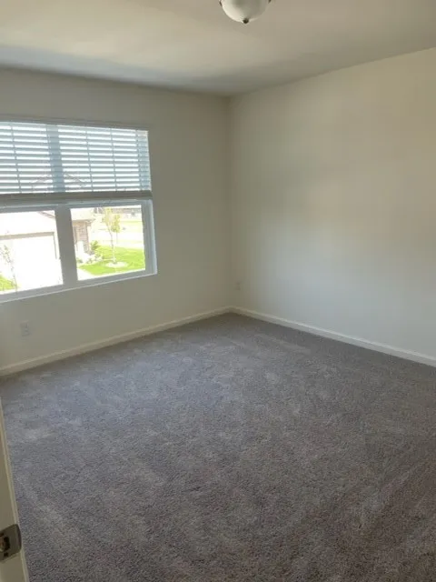 Spacious room featuring neutral carpeting and white walls