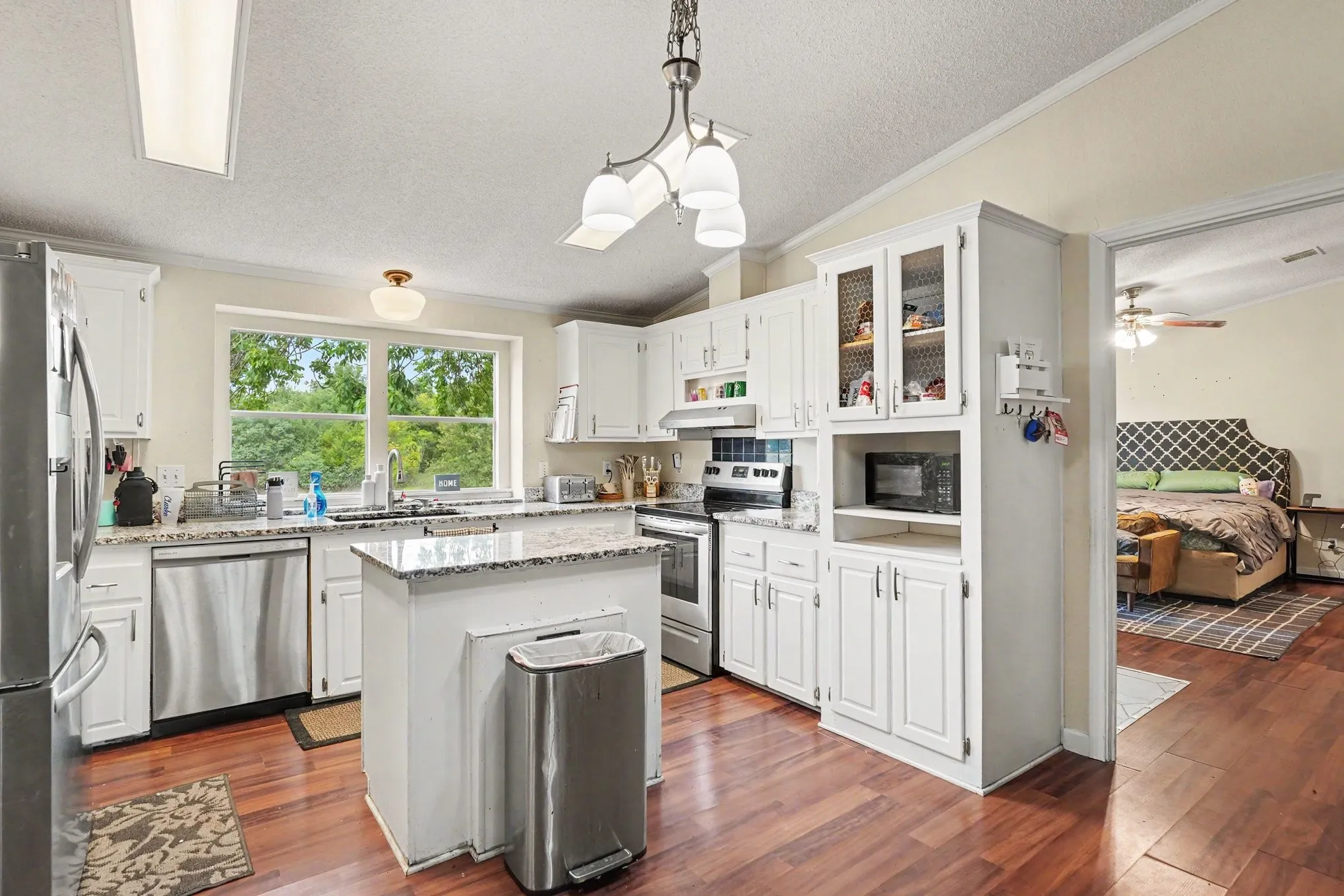 Kitchen featuring wood-finish flooring, white cabinetry, a central island, and stainless steel appliances