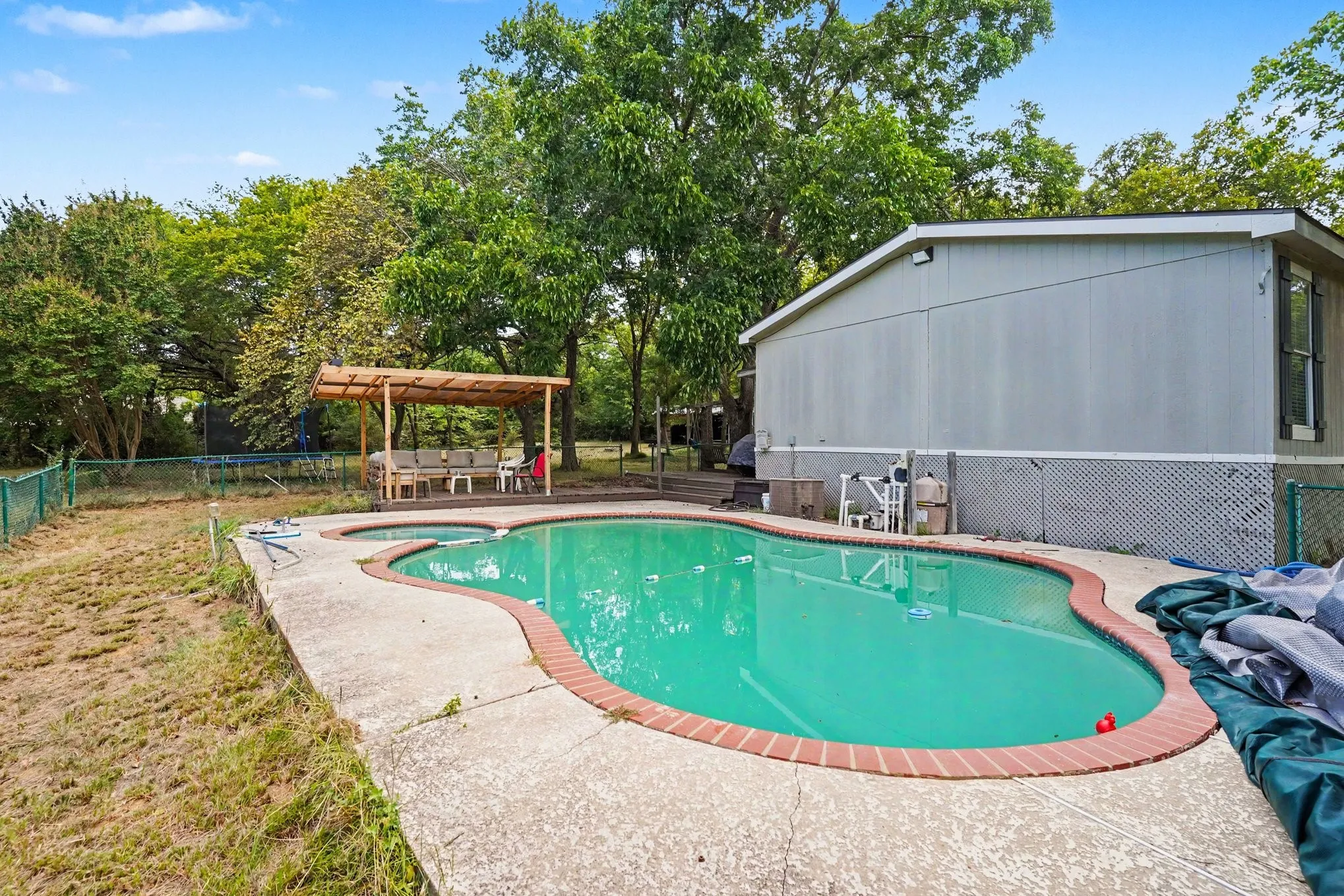 Sparkling resort-style pool with kidney-shaped design and brick decking, surrounded by mature landscaping and shade trees