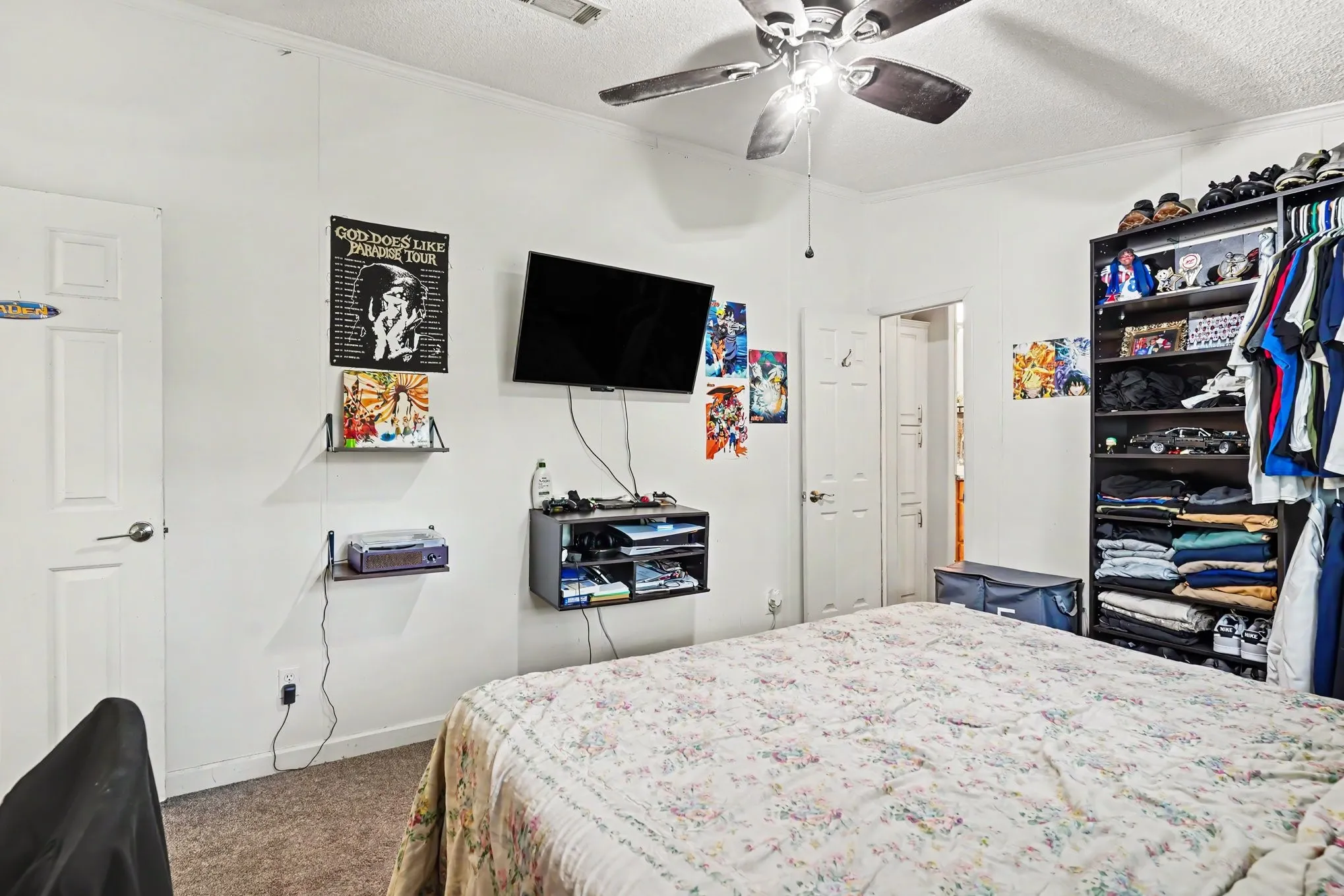 Carpeted bedroom featuring a ceiling fan with integrated lighting, wall-mounted shelving, and white paneled doors