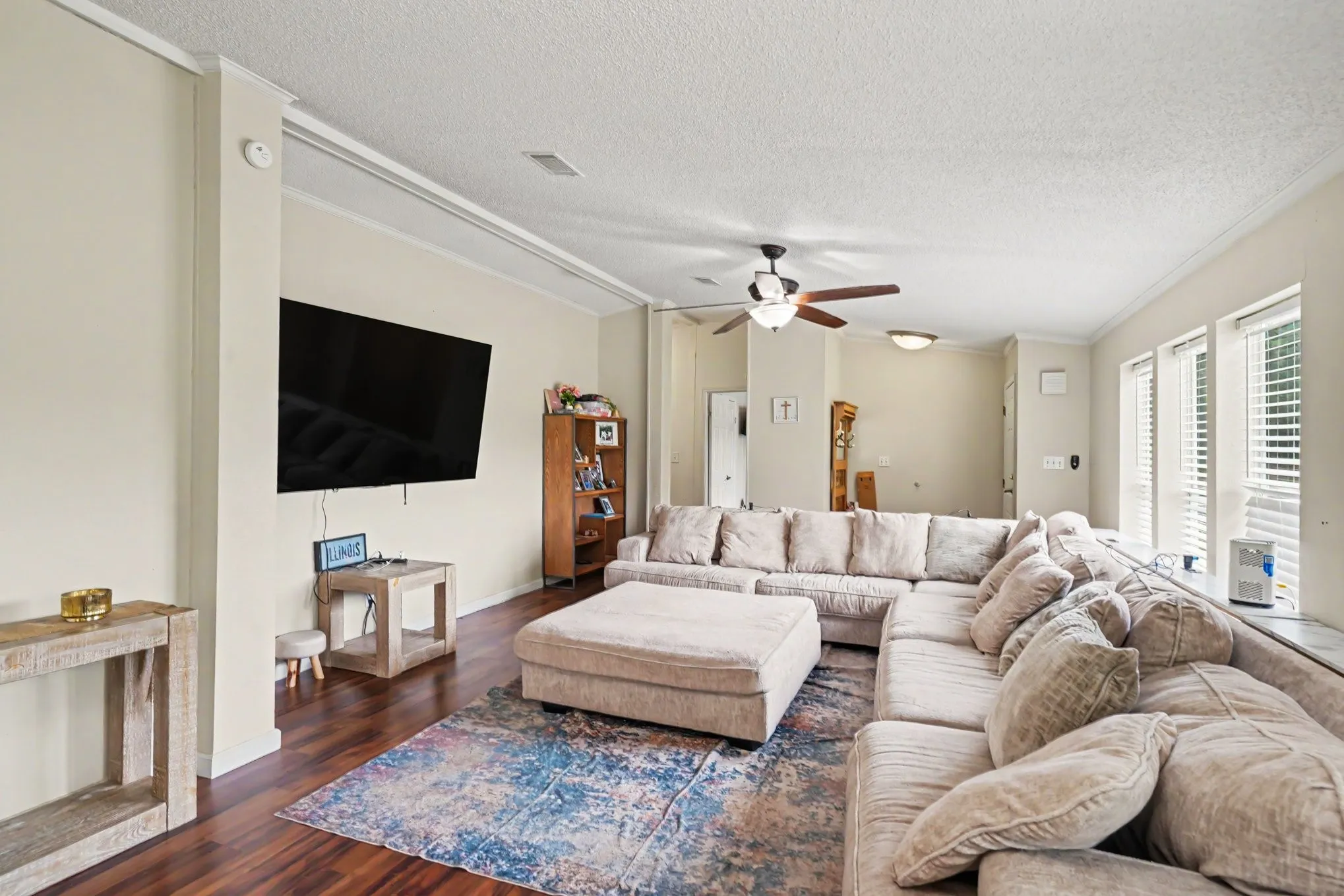 Spacious living room featuring a sectional seating arrangement, wood-finish flooring, and a blue-toned area rug