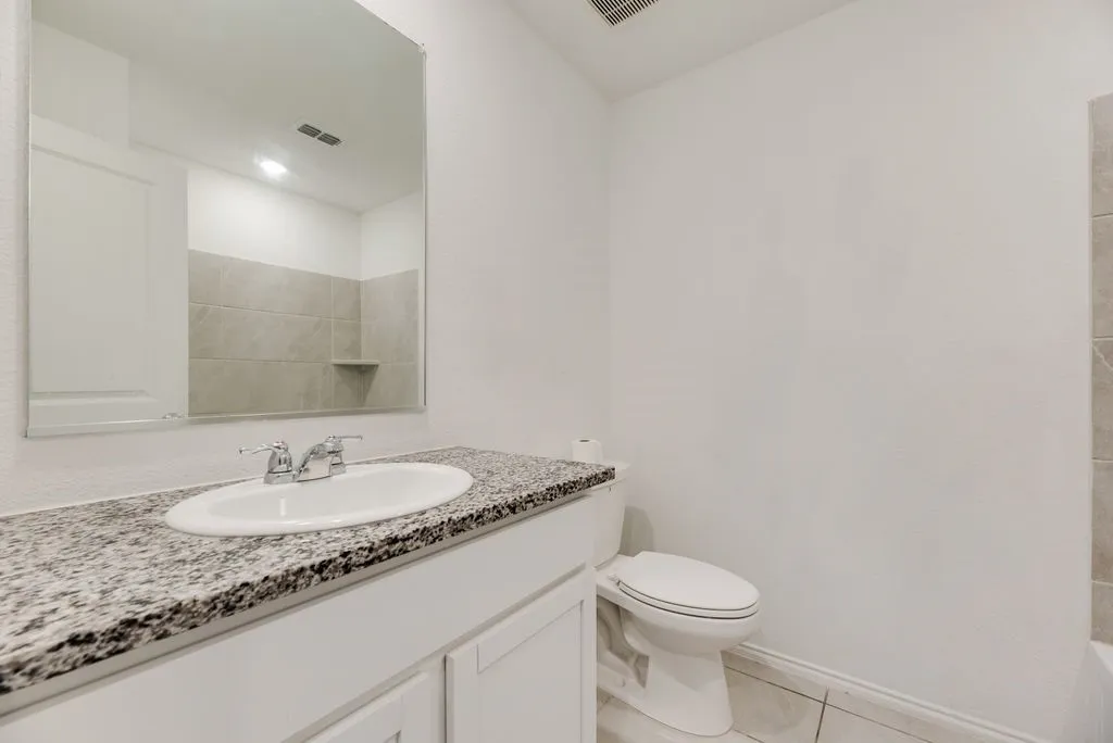 Bathroom vanity with a granite-style countertop, undermount sink, and chrome fixtures