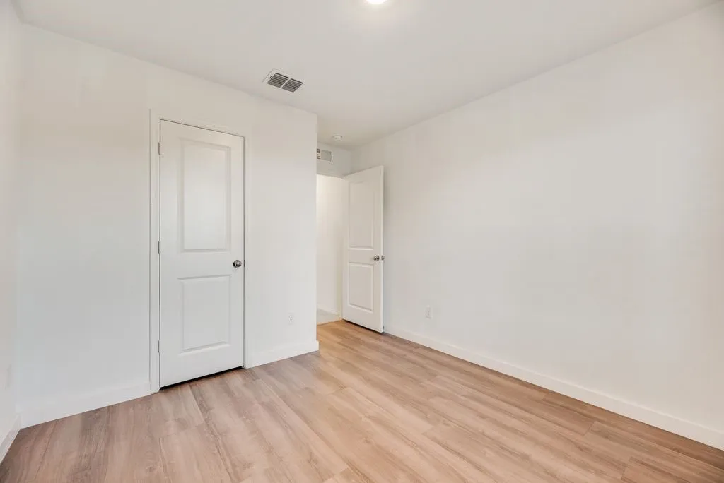 Room featuring wood-finish flooring, white painted walls, and white trim